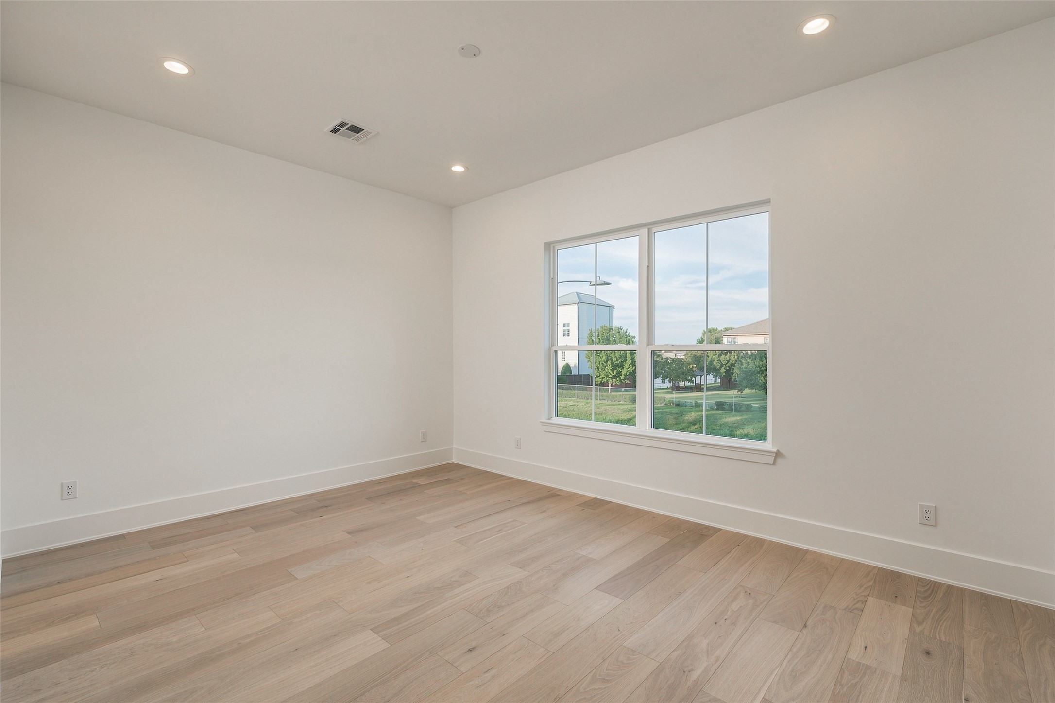 A generously proportioned secondary bedroom offers flexibility for a variety of layouts, with a wide window bringing in natural light and views toward the backyard.