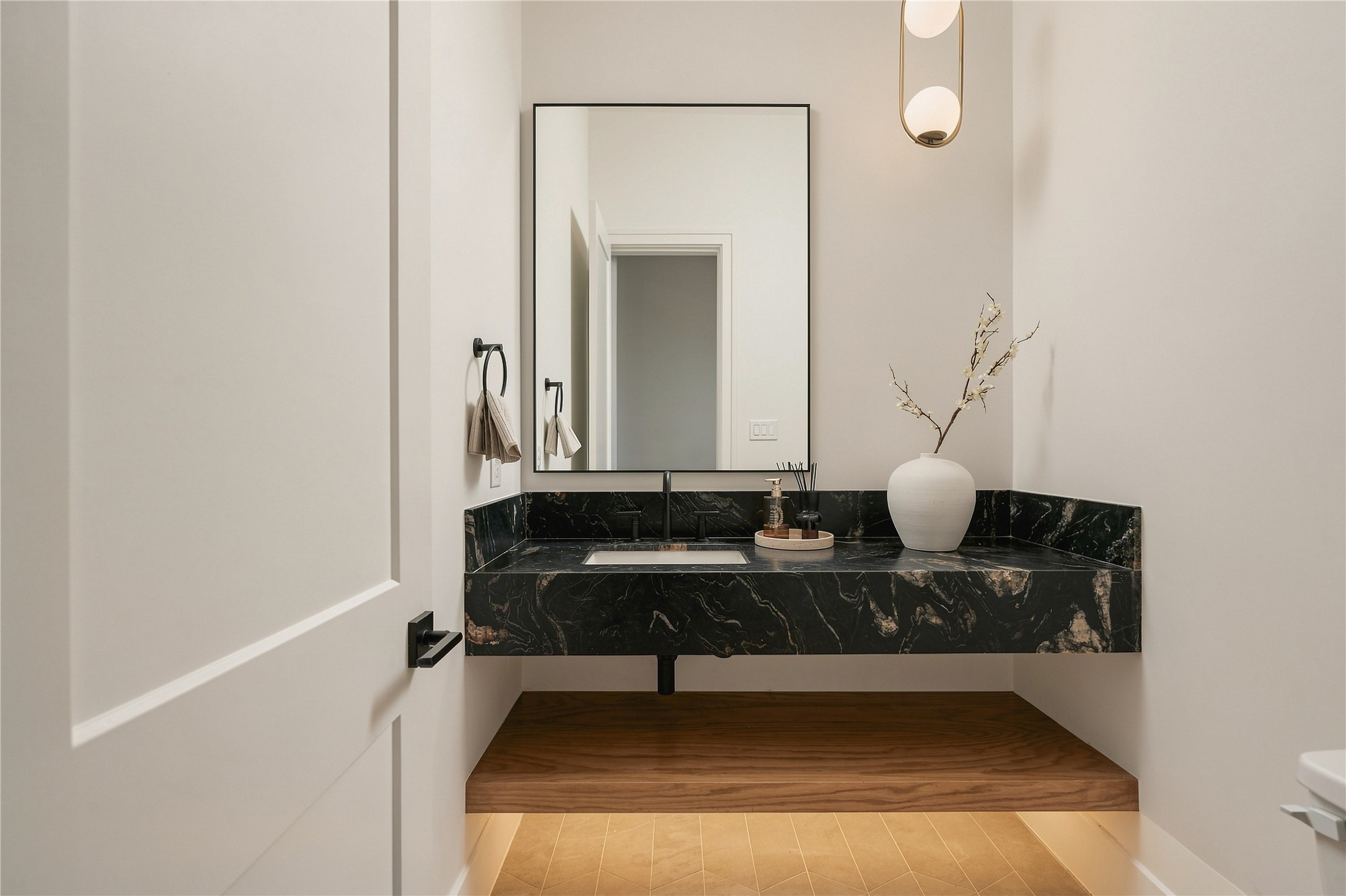 A powder room designed as its own moment, where a floating vanity wrapped in Titanium Quartzite brings drama and sculptural presence to the compact space.