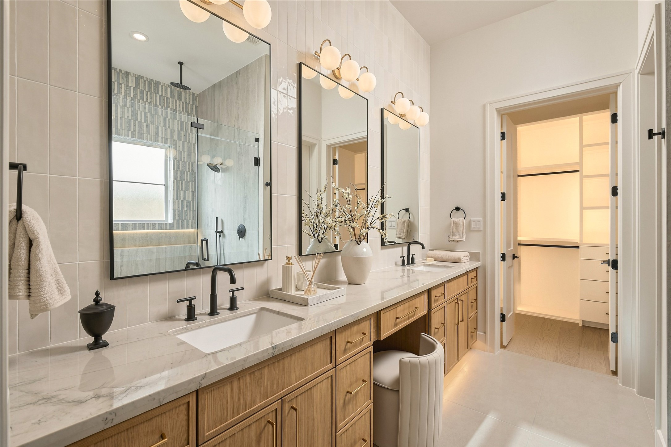 A closer look at the primary vanity showcases Mount Blanc Quartzite countertops, abundant storage, and a dedicated makeup station, with direct access to one of the suites two custom closets.
