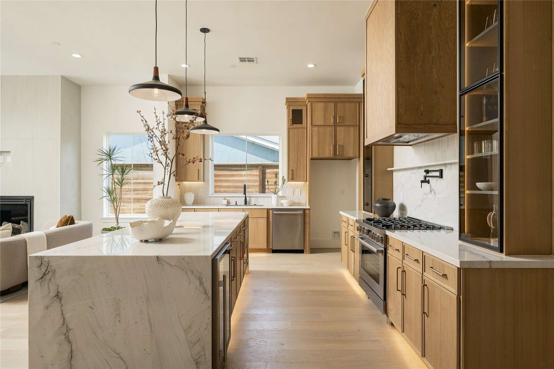Custom Midnight Glass Towers frame the Bosch range, complemented by a white oak vent hood and illuminated cabinetry that gives the kitchen a distinctly tailored, furniture-like quality.