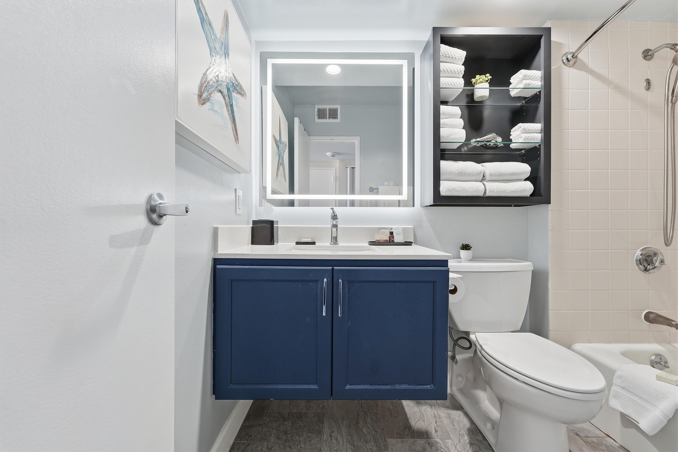 Open shelving provides handy bathroom storage, while coordinating finishes carry the coastal style throughout.