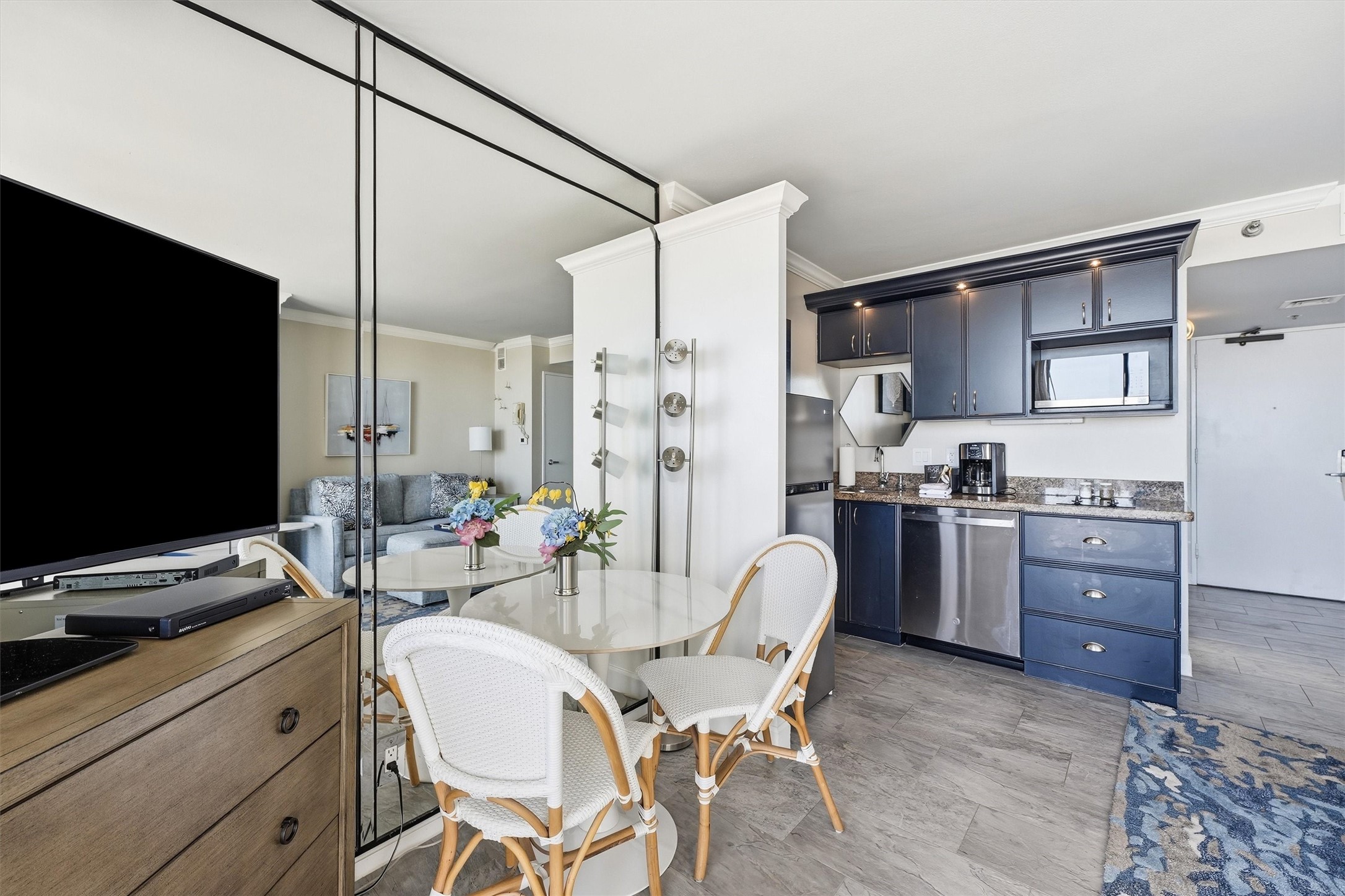 A mirrored accent wall enhances the bright dining area, conveniently located beside the kitchenette.