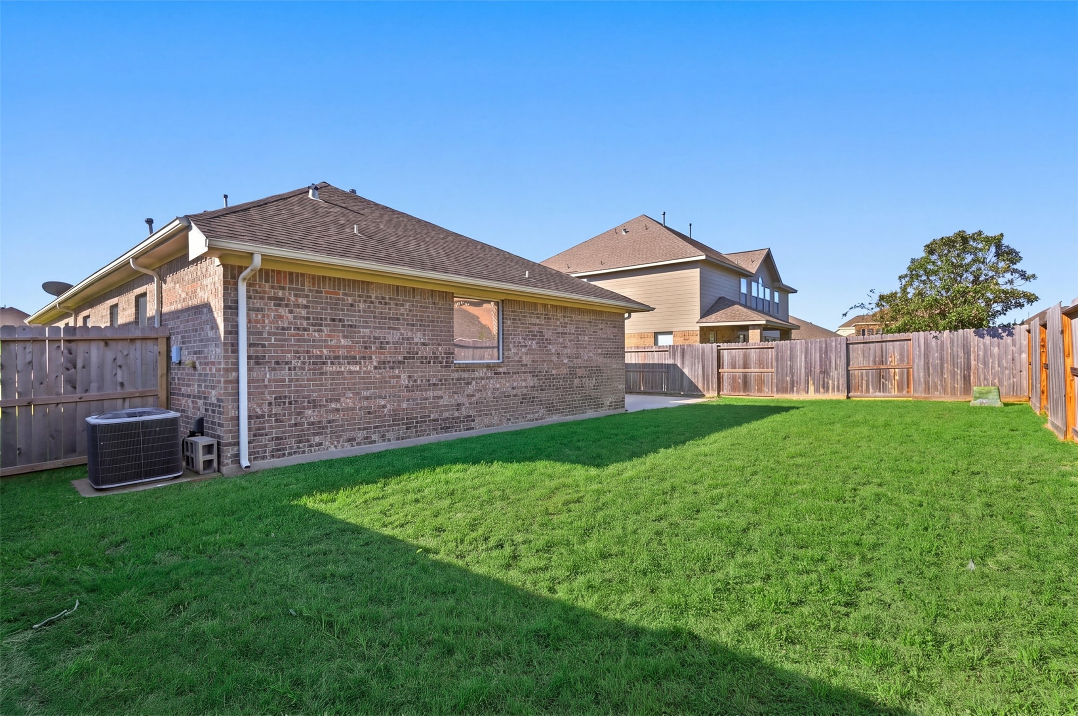 Spacious backyard with lush green lawn, perfect for outdoor activities and relaxation, surrounded by a sturdy wooden fence for added privacy.