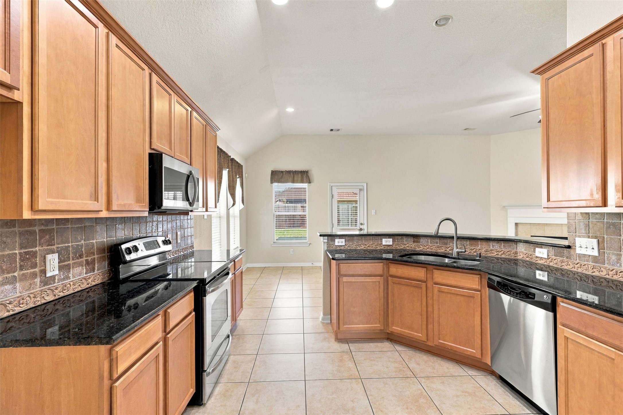 Spacious kitchen with sleek granite countertops, stainless steel appliances, and rich wood cabinetry, perfect for culinary enthusiasts.