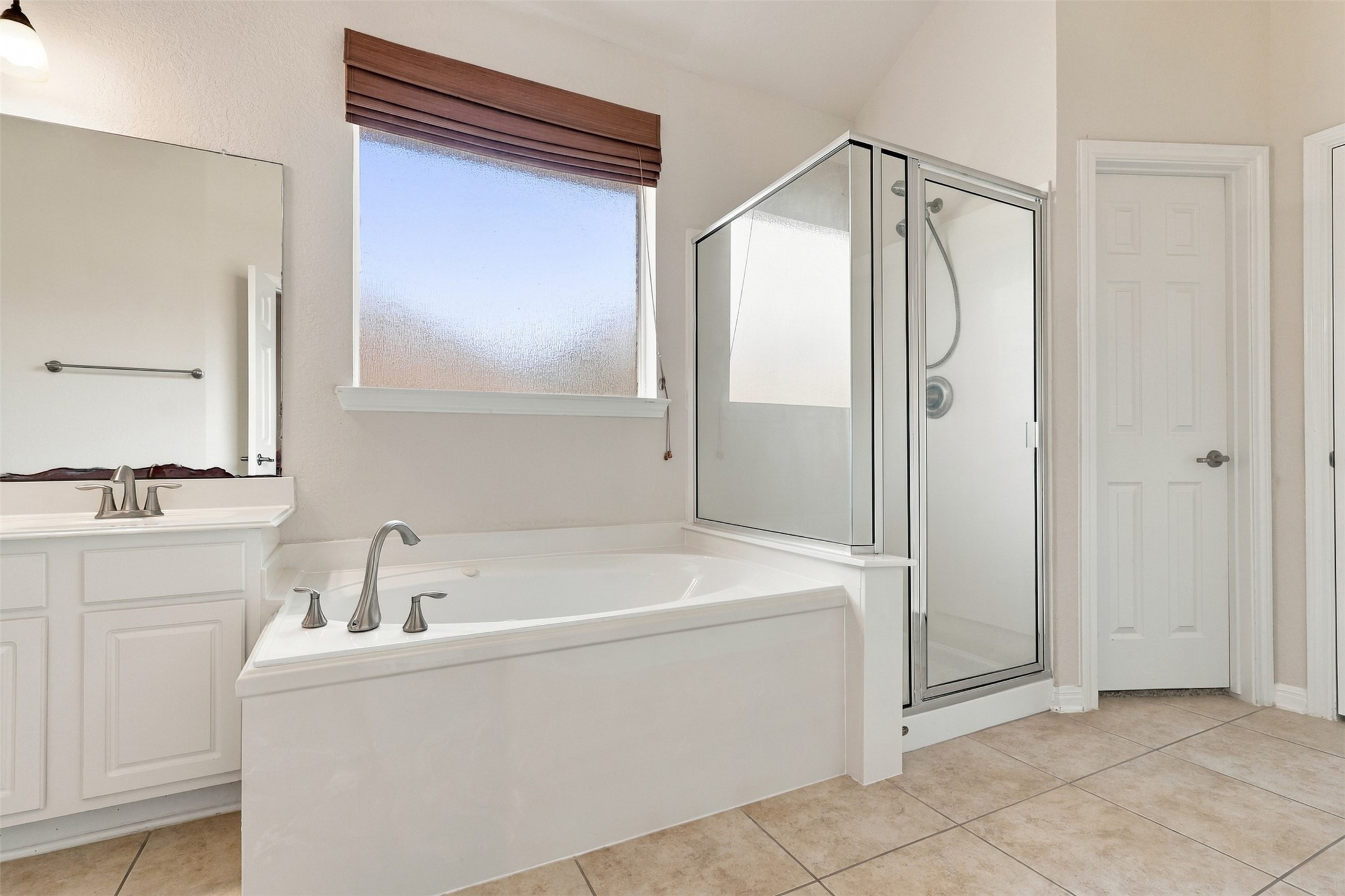Spacious bathroom featuring a modern glass-enclosed shower, a large soaking tub, and elegant tile flooring.