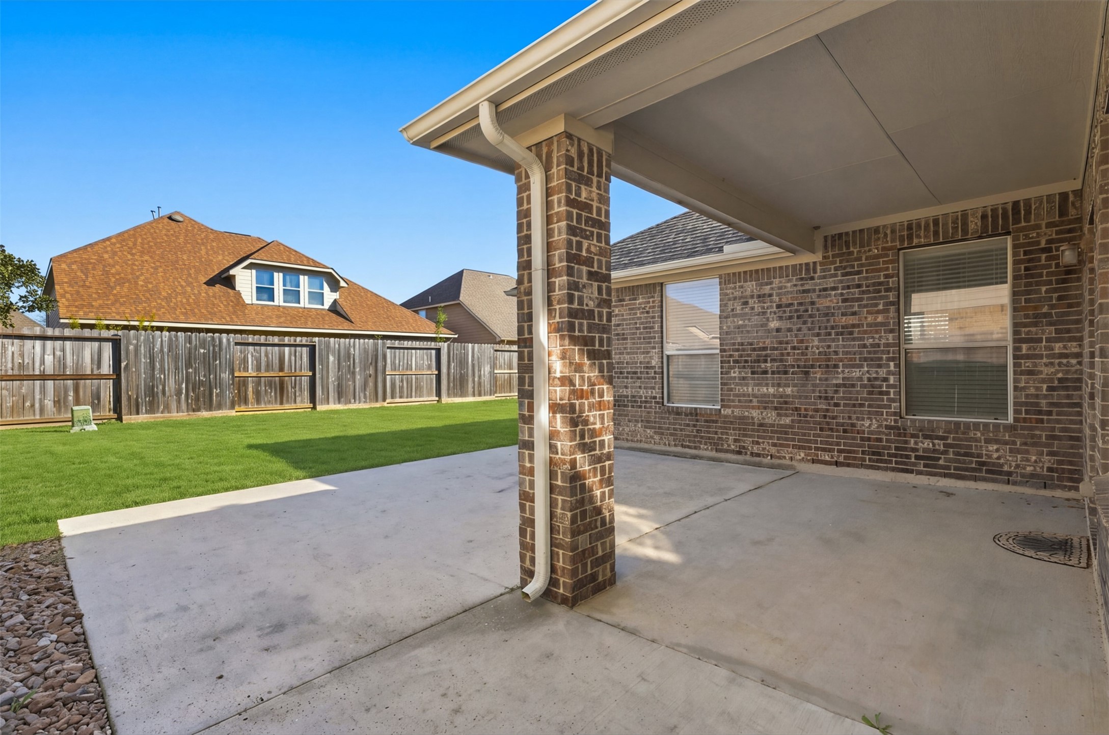 Large covered patio with a view of the fenced backyard, perfect for outdoor entertaining and relaxation.