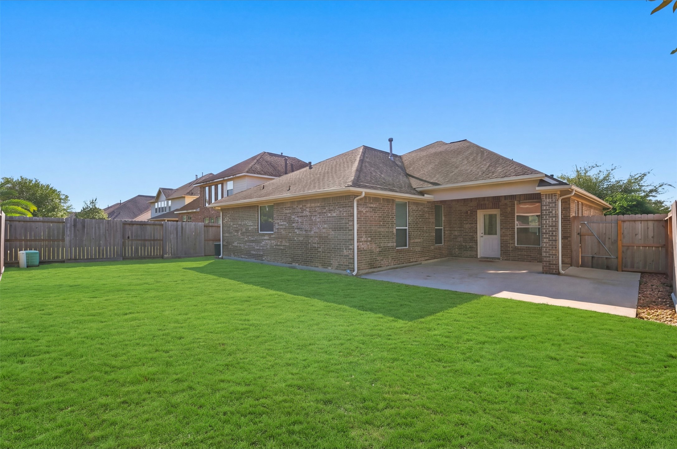 Expansive backyard with a lush lawn and a cozy patio area, perfect for outdoor gatherings and relaxation.