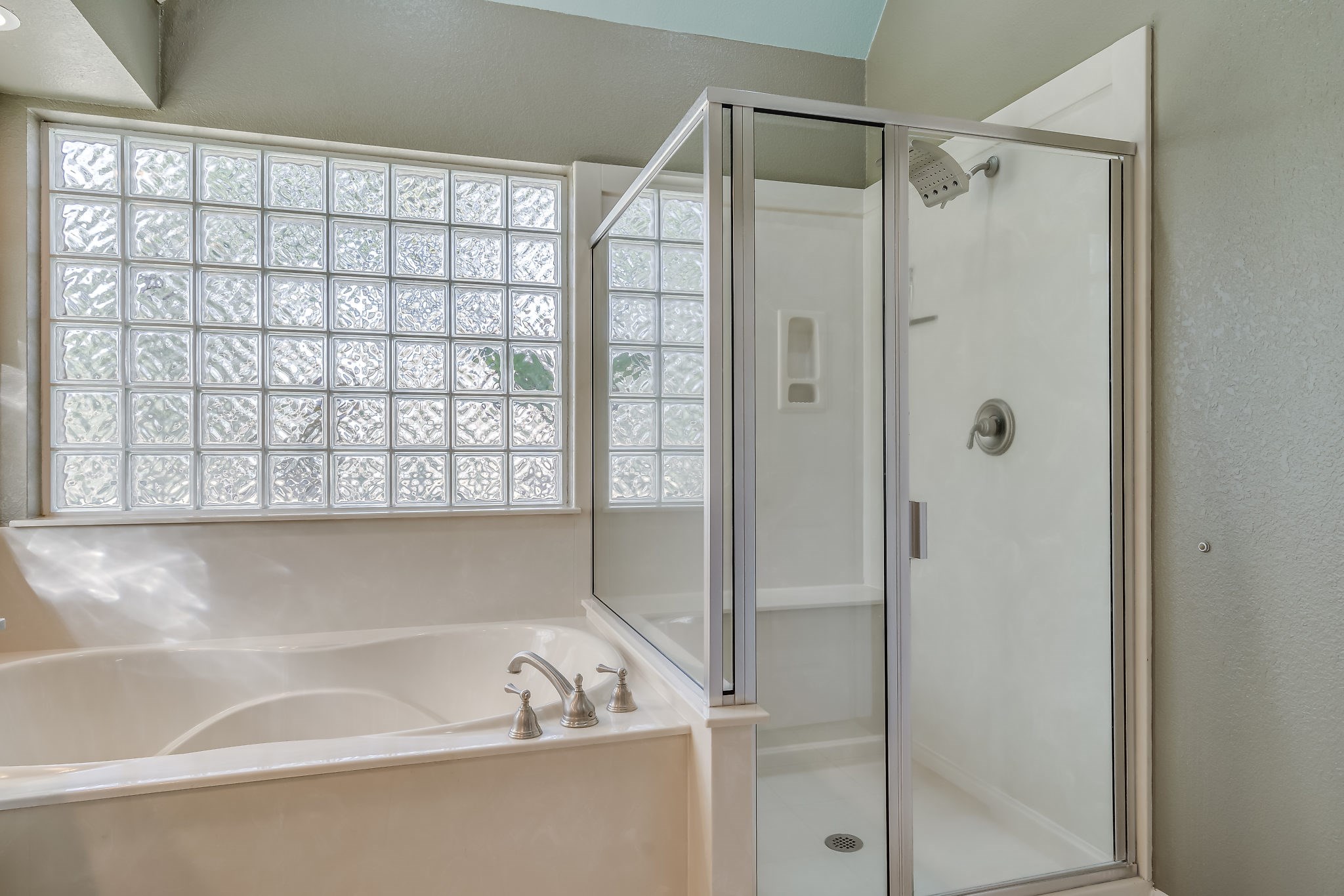 Experience ultimate relaxation with a luxurious soaking tub and sleek separate shower, bathed in natural light through elegant glass block windows