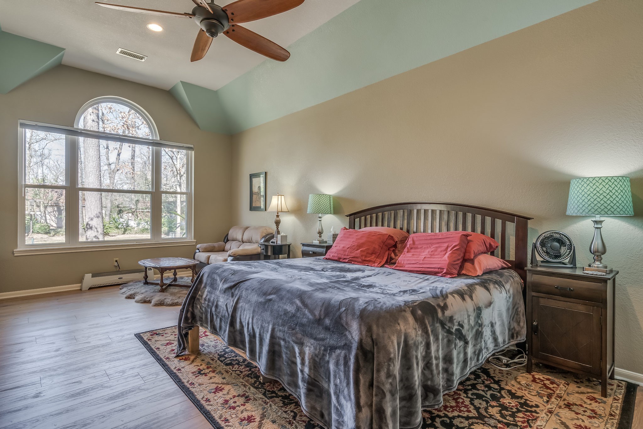 Experience serene comfort in this primary suite featuring a ceiling fan and a large window with picturesque backyard views