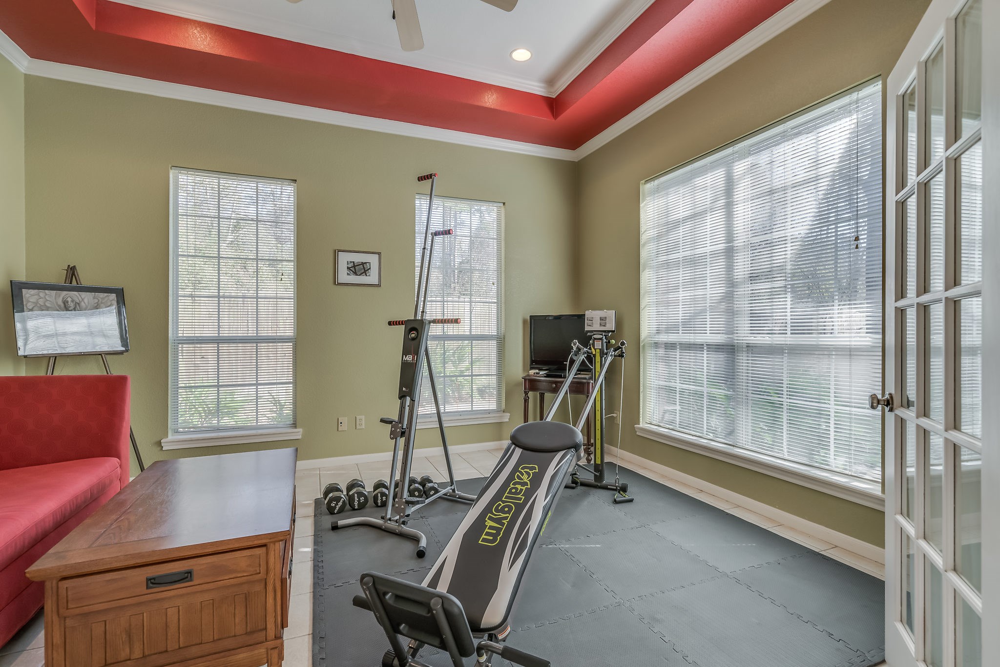 Discover your perfect space with this versatile room featuring elegant French doors, ceiling fan, and tile flooringideal for a home office or workout space