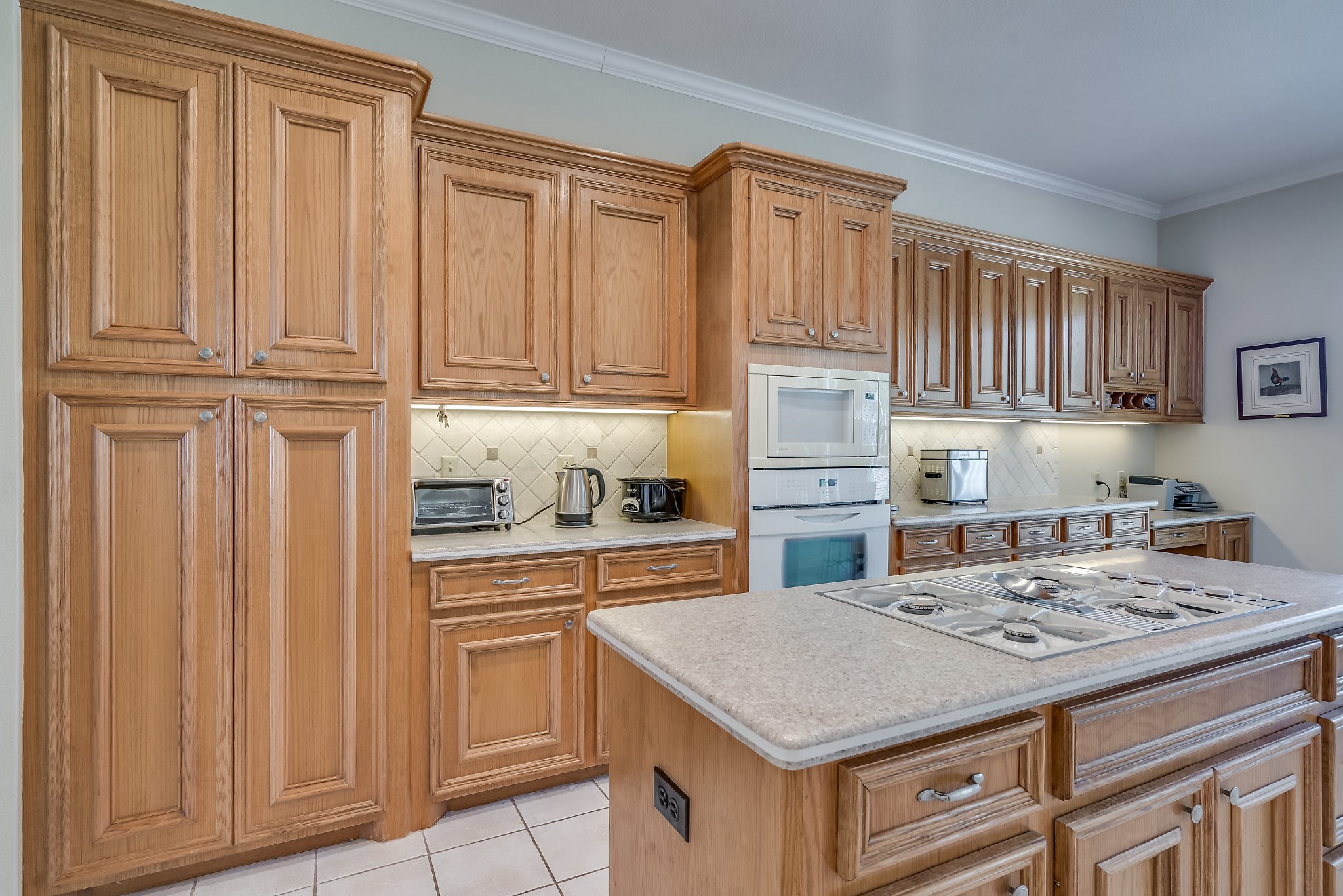 Discover a beautifully designed kitchen featuring built-in cabinetry, sleek Silestone countertops, elegant tile flooring, and a convenient desk area for seamless functionality