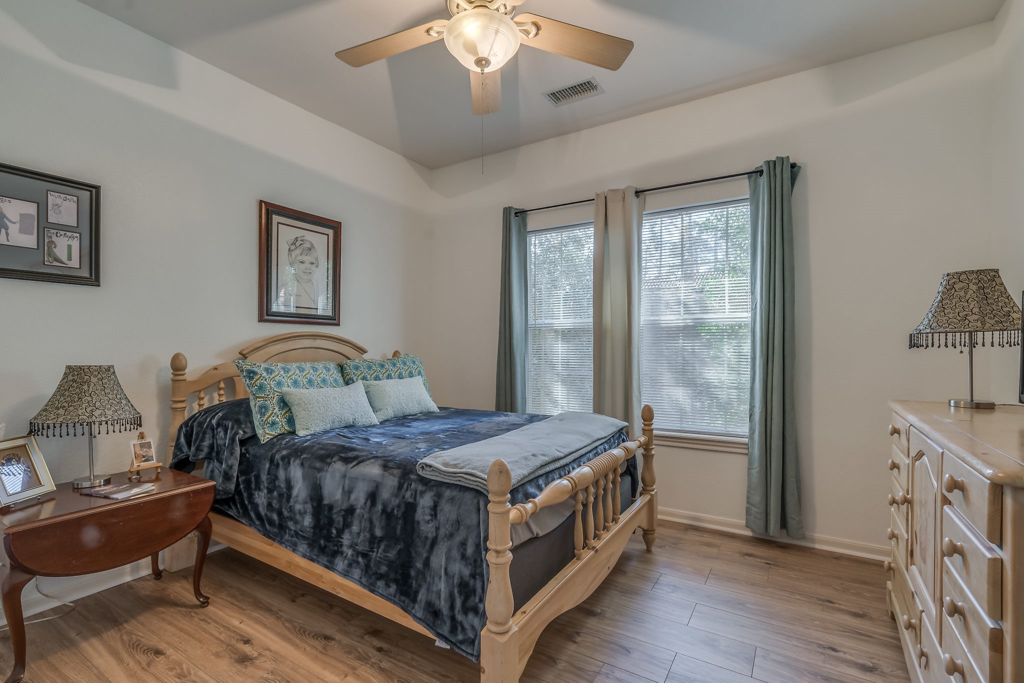 Experience comfort and style in Bedroom 3, featuring a ceiling fan, elegant tray ceiling, and laminate wood floors