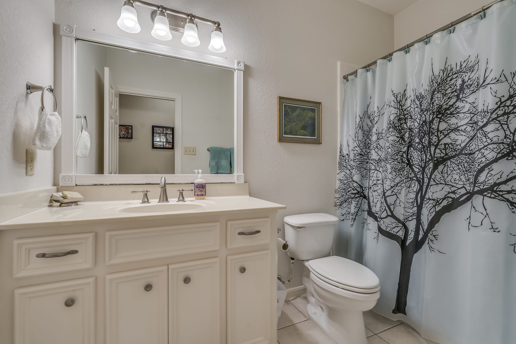This charming guest bathroom features elegant tile flooring and a convenient tub/shower combo, with an additional half bath (not pictured) off the dining area providing extra convenience for guests