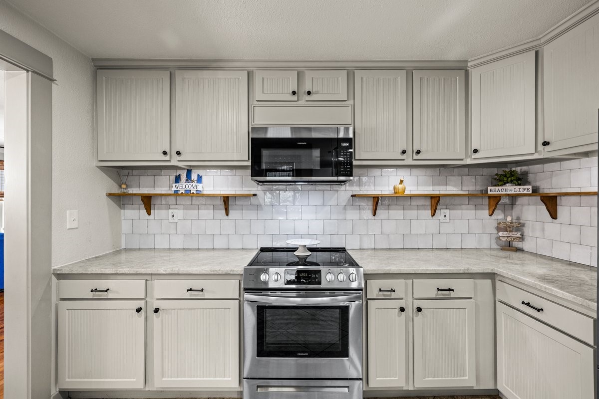 The kitchen features gorgeous quartzite countertops and stylish open shelving