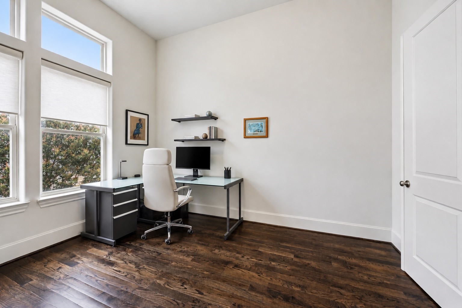 Soaring ceilings and oversized windows fill this dedicated home office with natural light, while rich hardwood floors bring warmth to the bright, airy space. Generous proportions leave room to create a polished workspace tailored to your needs.