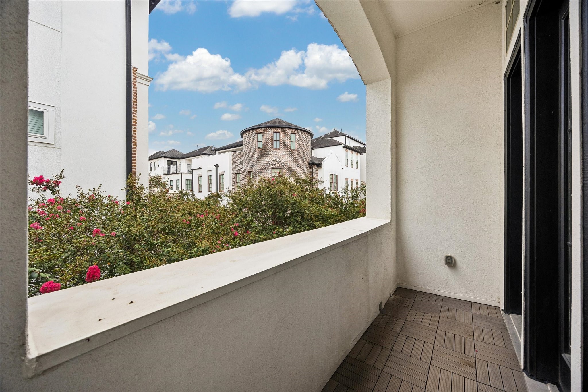 A private covered balcony creates a quiet outdoor escape with views across the landscaped community and surrounding architecture, offering a peaceful spot to enjoy fresh air without leaving home.