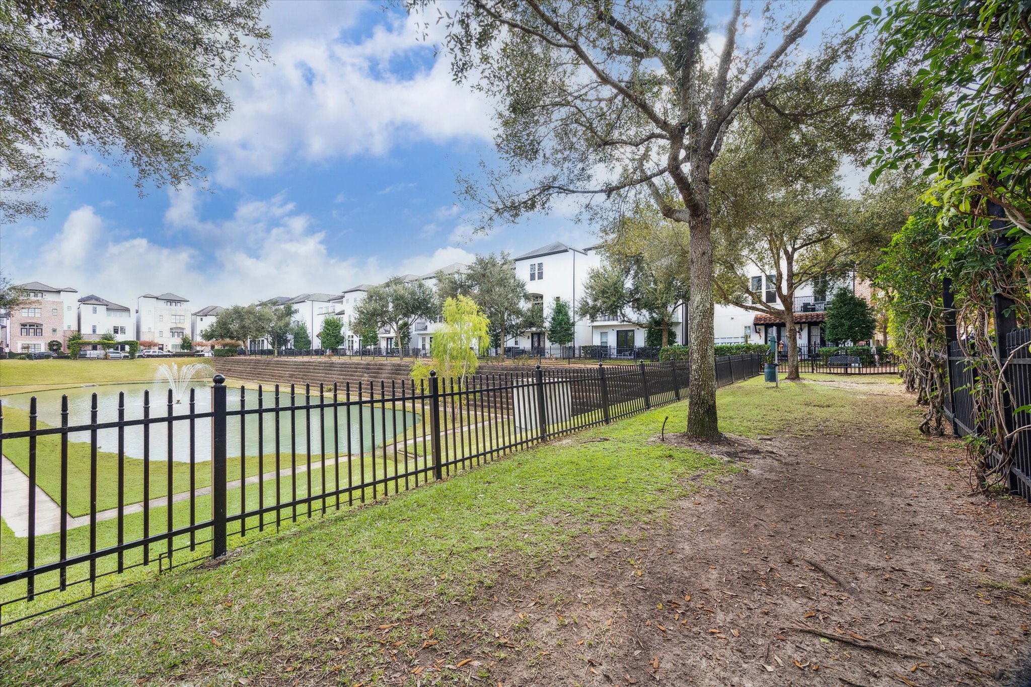 Community dog park set alongside a landscaped greenbelt and pond, offering shaded walking paths and open space for pets to roam. Fenced surroundings and mature trees create a peaceful, well-maintained area designed for everyday use.