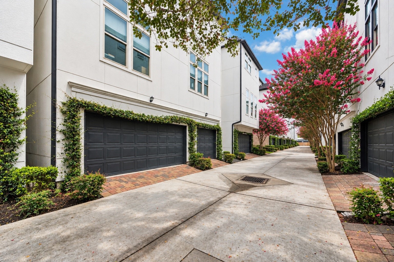 A private rear drive is framed by manicured landscaping, climbing greenery, and vibrant crepe myrtles, creating a polished arrival from every angle. Attached garages provide convenient access while preserving the communitys charming, pedestrian focused streetscape.