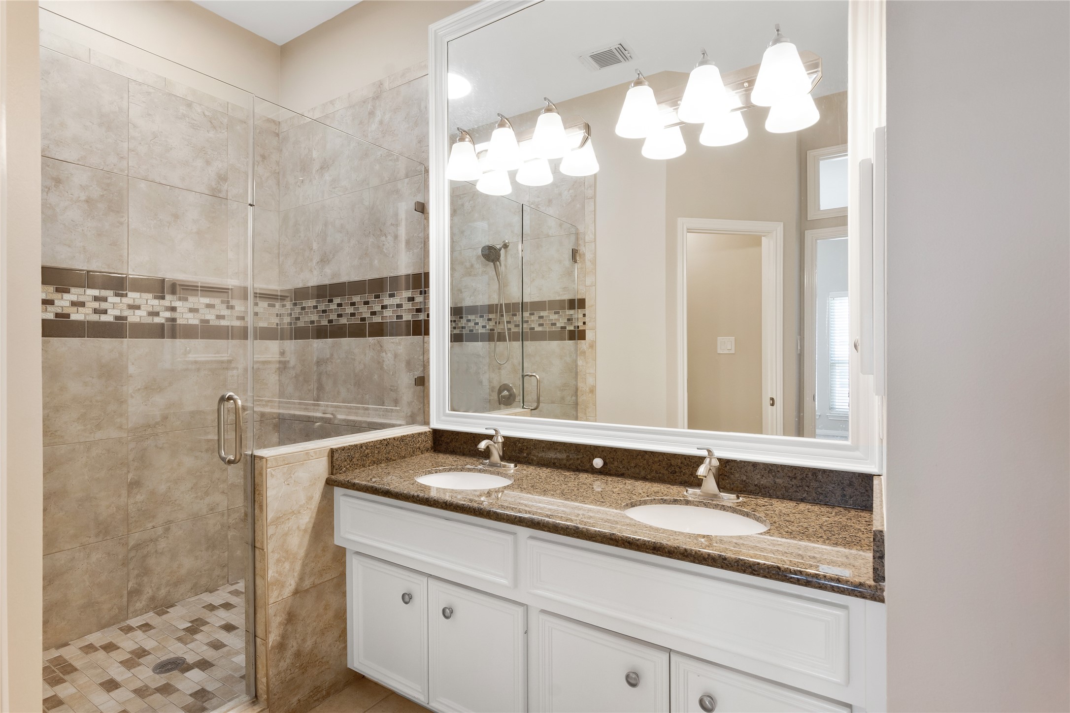 Primary Bath with dual vanity, granite countertop and large walk in tiled shower