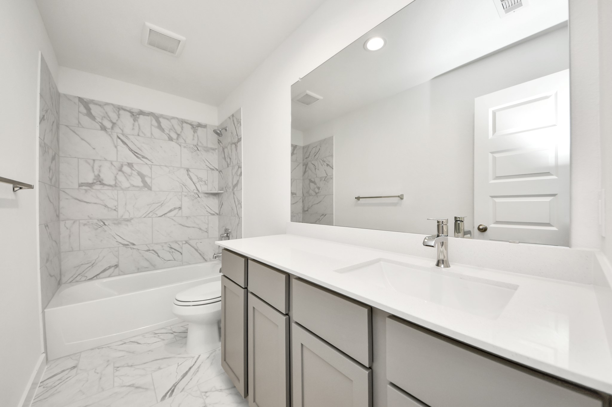 Secondary bath features tile flooring, bath/shower combo with tile surround, light stained wood cabinets, beautiful light countertop. Sample photo of completed home with similar floor plan. Actual colors and selections may vary.