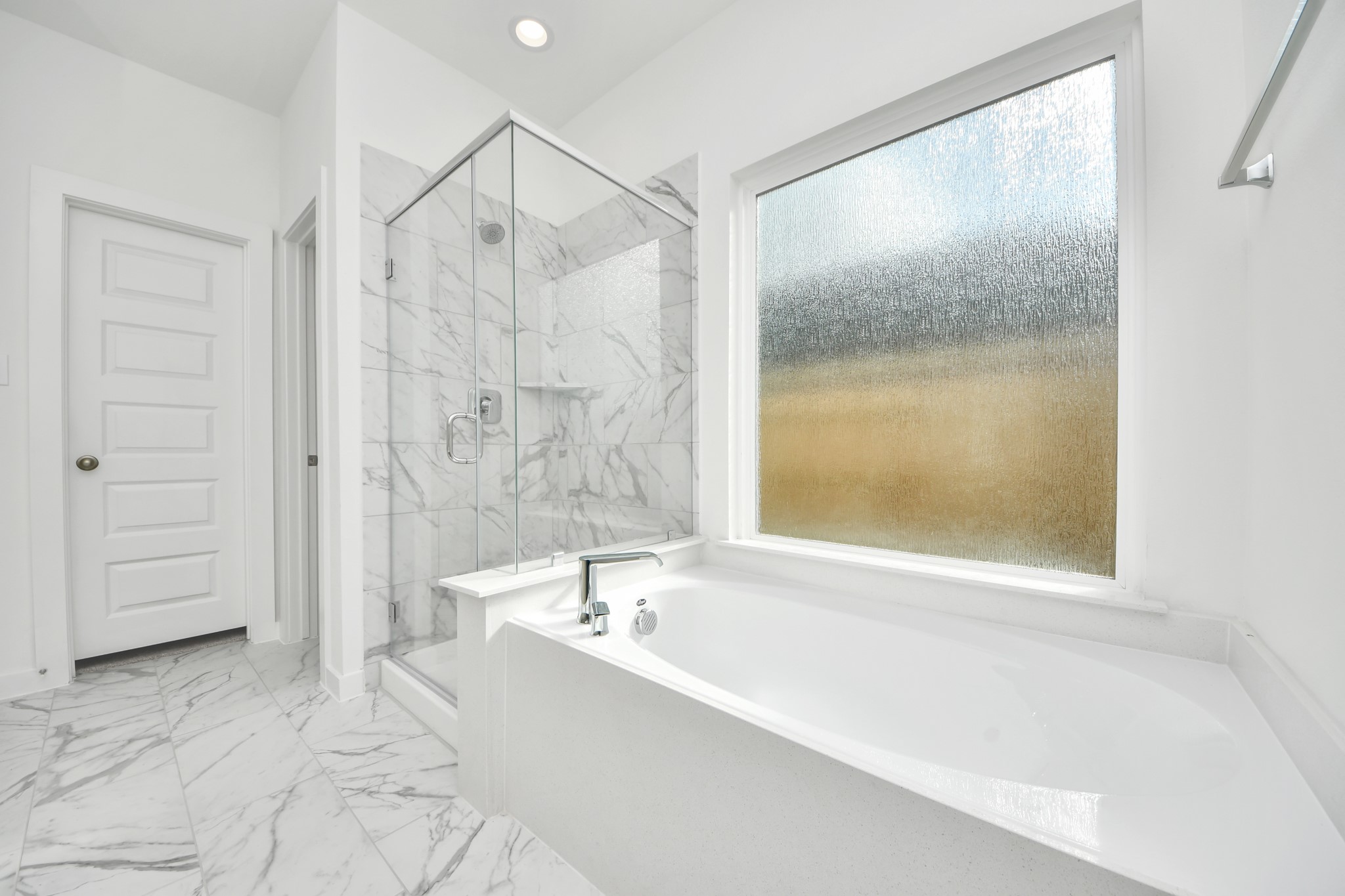 Escape to a spa-like oasis in this primary bathroom. Enjoy a walk-in shower with tile surround, a separate garden tub with custom detailing, and an elegant vanity featuring light countertops, modern hardware, and beautiful recessed lights. Experience luxury and relaxation in every detail. Sample photo of completed home with similar floor plan. Actual colors and selections may vary.