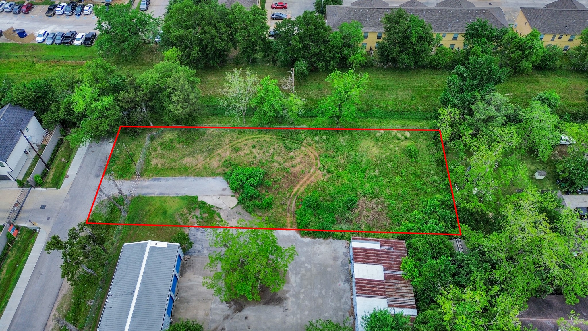 This aerial photo shows a rectangular plot of land outlined in red, featuring a mix of grass and trees. It's situated in a residential area with nearby roads and buildings, offering potential for development. This aerial photo shows a rectangular plot of land outlined in red, featuring a mix of grass and trees. It's situated in a residential area with nearby roads and buildings, offering potential for development.