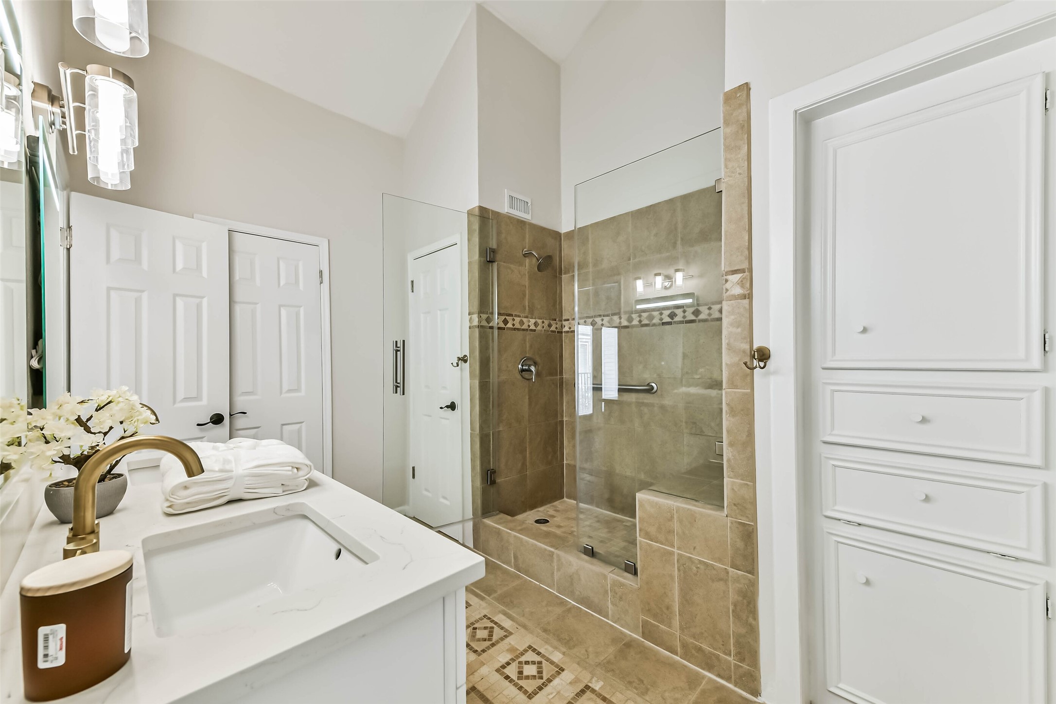 The primary shower features tile surround and a seamless glass door.