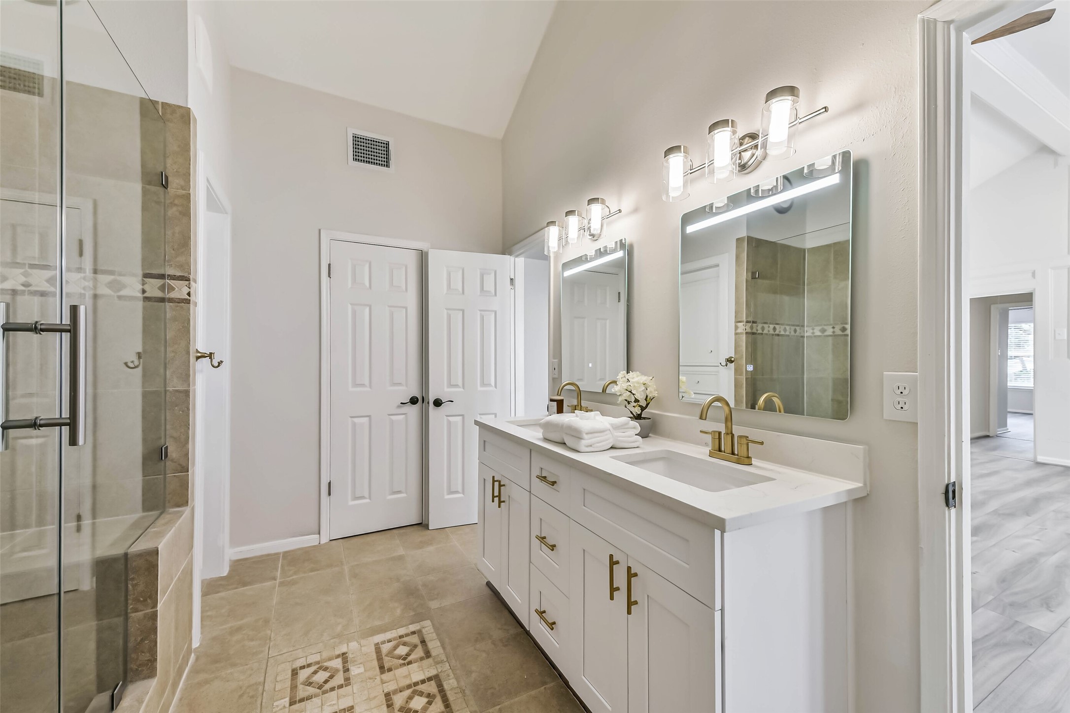 There are double sinks, tile floors and a linen cabinet in the primary bath.
