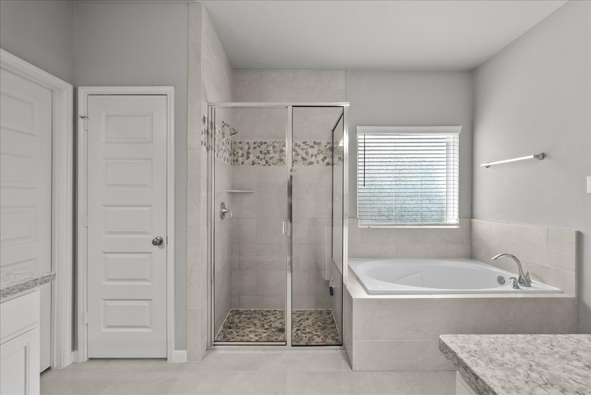 Primary bath features dual vanities, walk-in shower, soaking tub and a walk-in closet