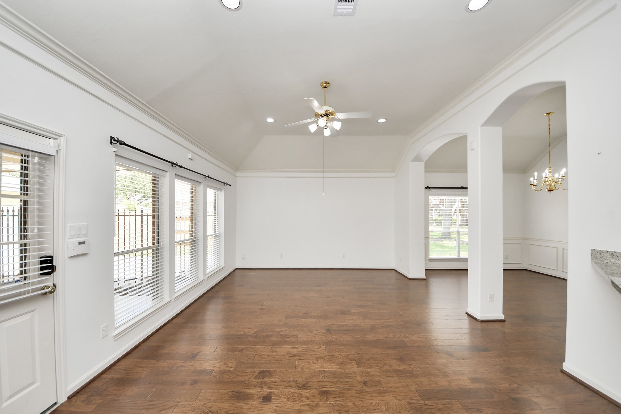 Spacious, light-filled living area with elegant hardwood floors, vaulted ceilings, and stylish arched entryways.