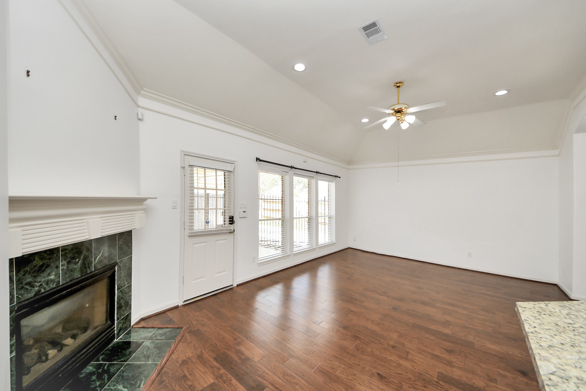 Spacious bedroom with elegant wood flooring, a cozy fireplace, and abundant natural light from large windows, perfect for relaxation and entertaining.