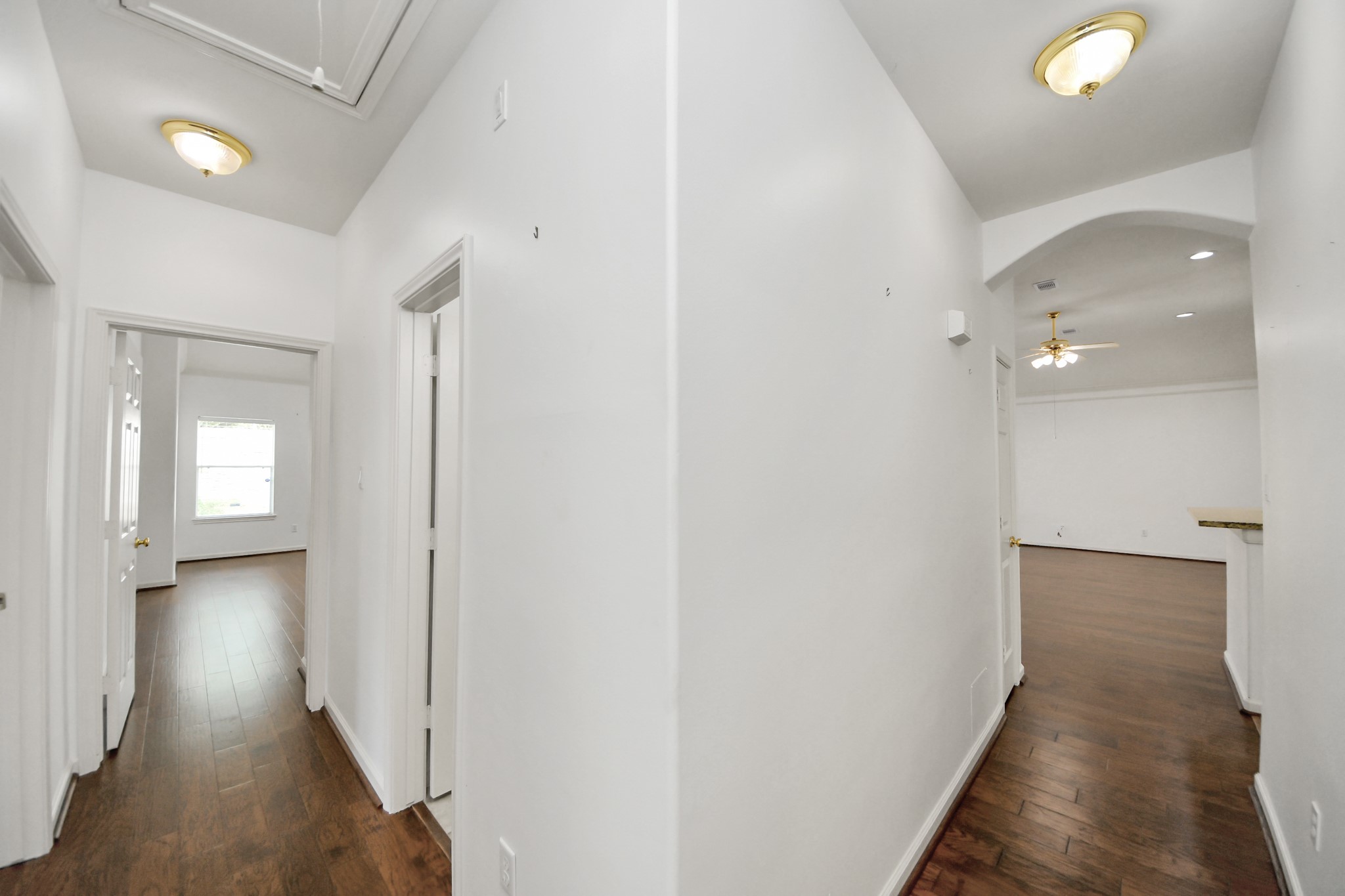 Bright and spacious hallway with warm wood flooring, leading to multiple rooms and featuring stylish ceiling lights.