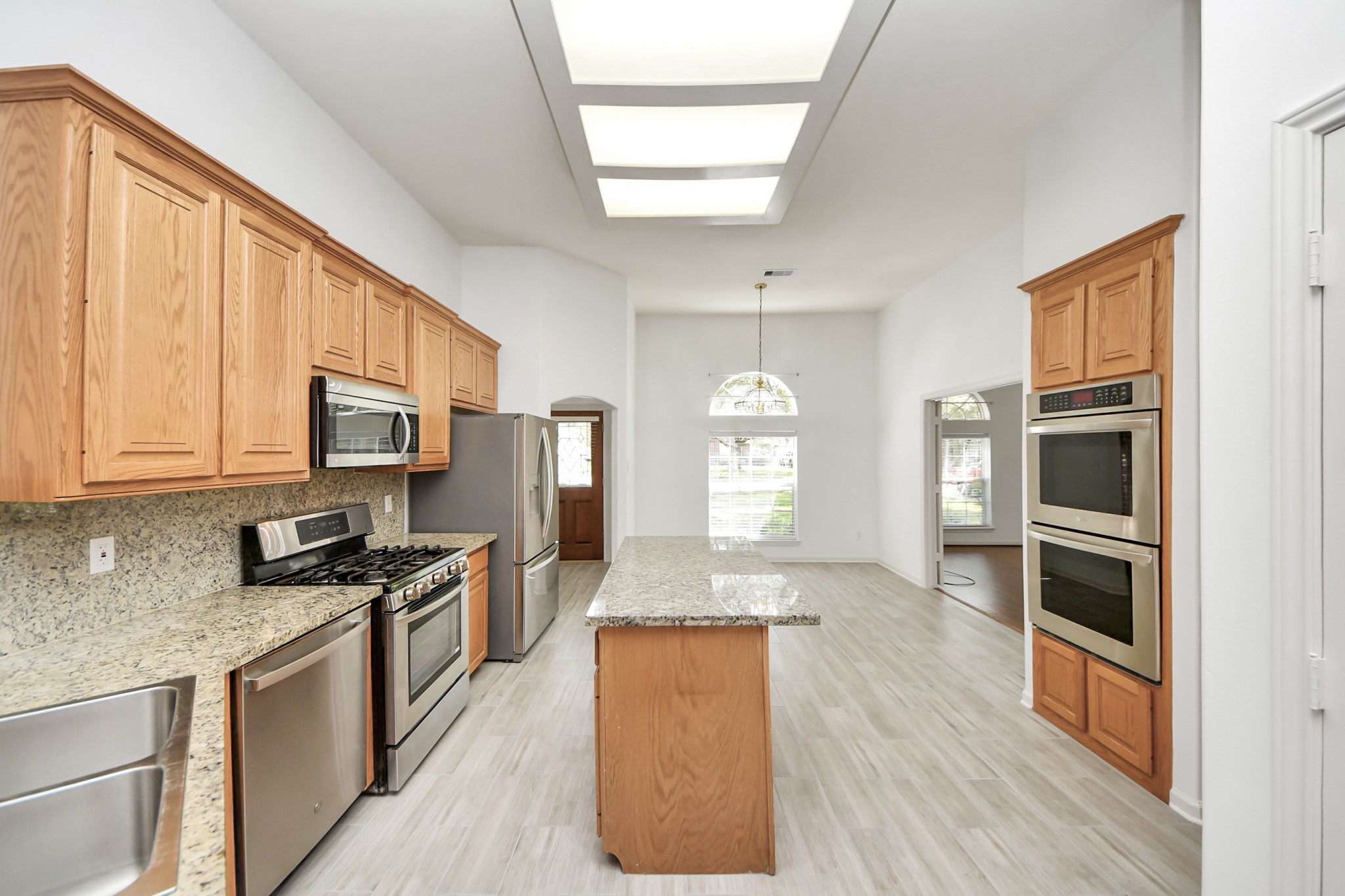 Spacious kitchen with granite countertops, modern stainless steel appliances, and abundant natural light, featuring a central island and warm wood cabinetry.