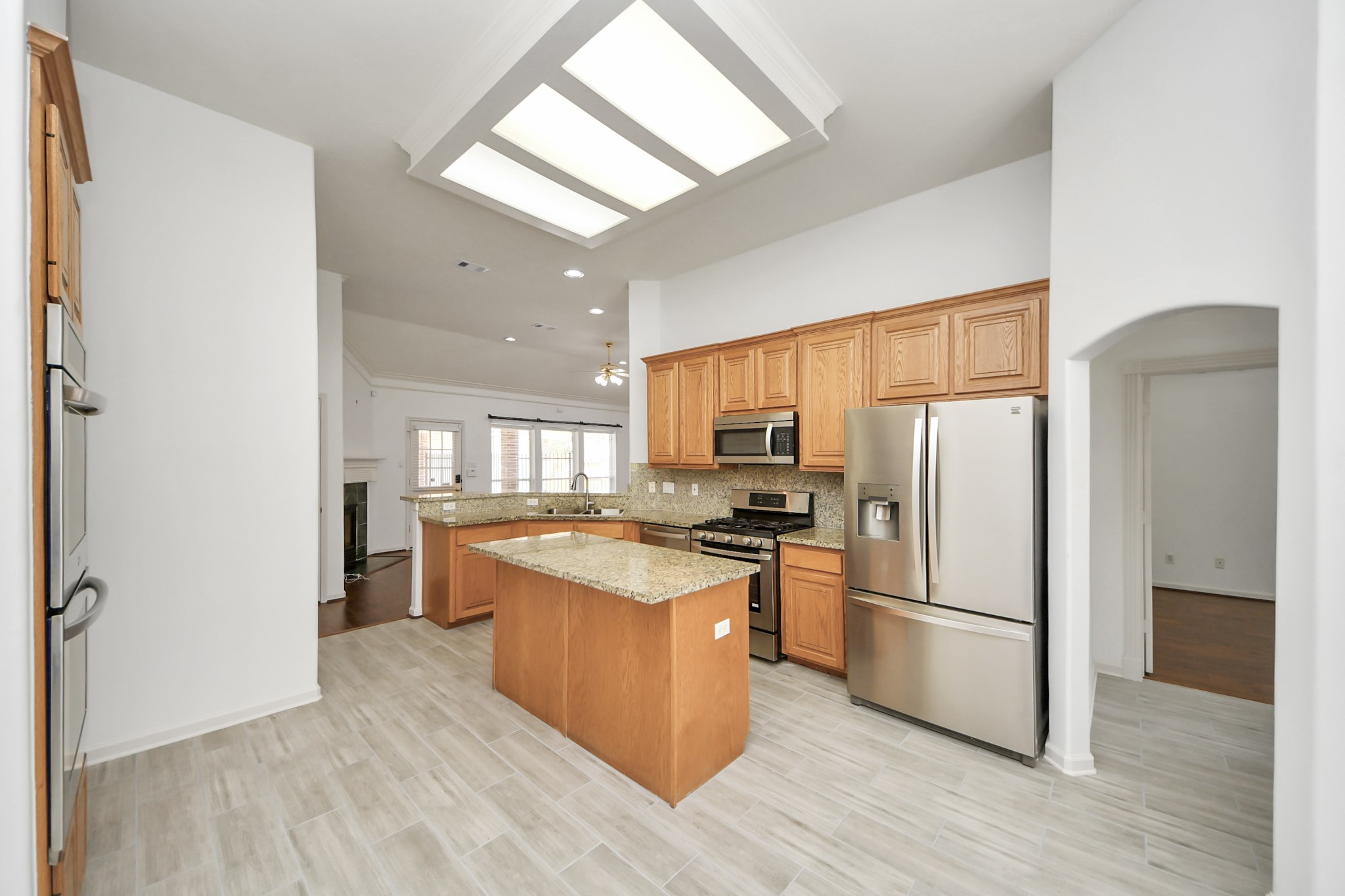 Spacious kitchen featuring modern stainless steel appliances, granite countertops, and ample wooden cabinetry, accented by elegant tile flooring and recessed lighting.