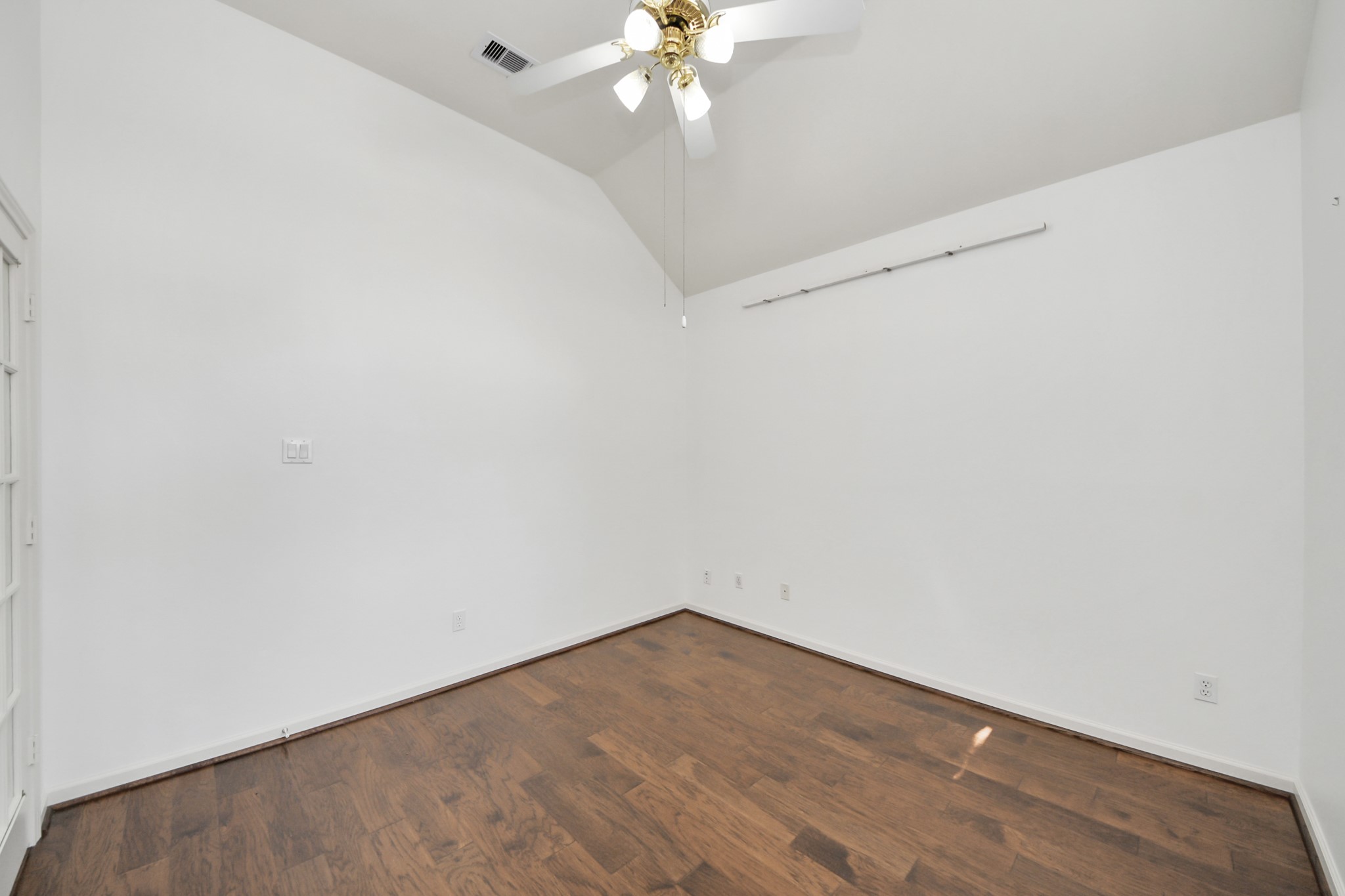 Bright and inviting room with vaulted ceilings, elegant hardwood flooring, and a ceiling fan, perfect for a cozy retreat or creative workspace.