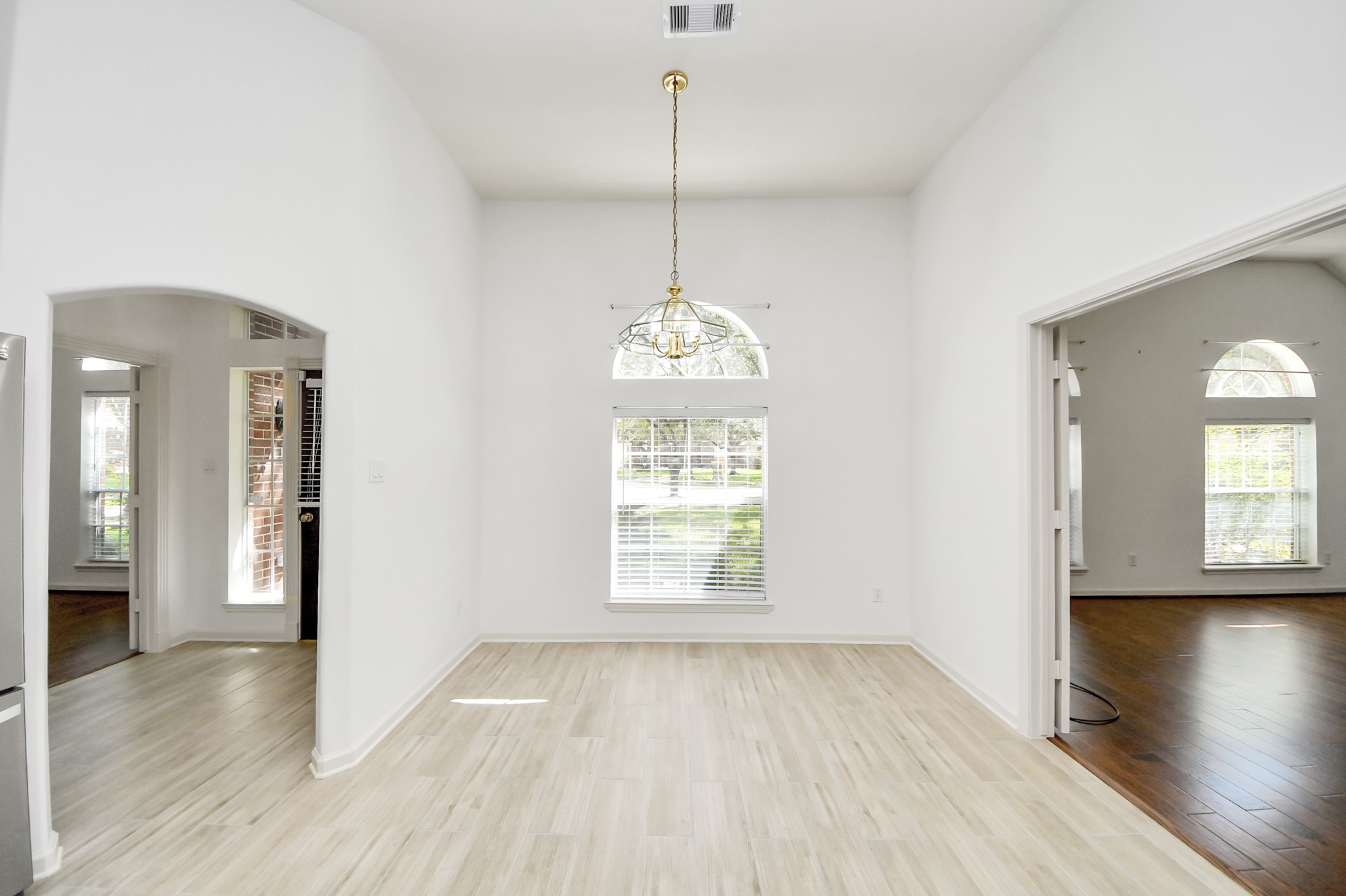Bright and airy room with elegant light wood flooring, high ceilings, and large arched windows allowing abundant natural light.