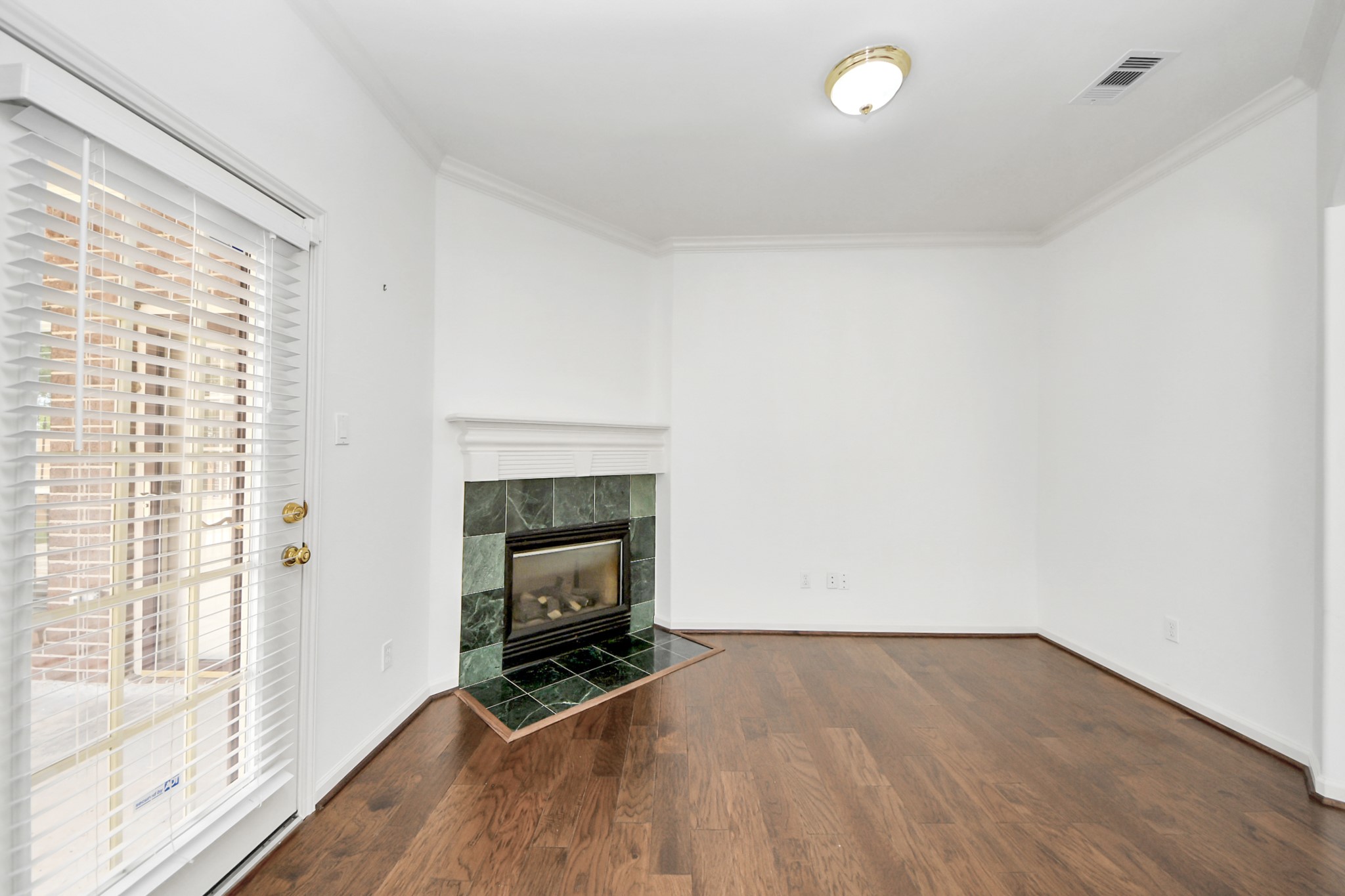 Charming Bedroom with elegant hardwood floors, a cozy corner fireplace, and abundant natural light from French doors.