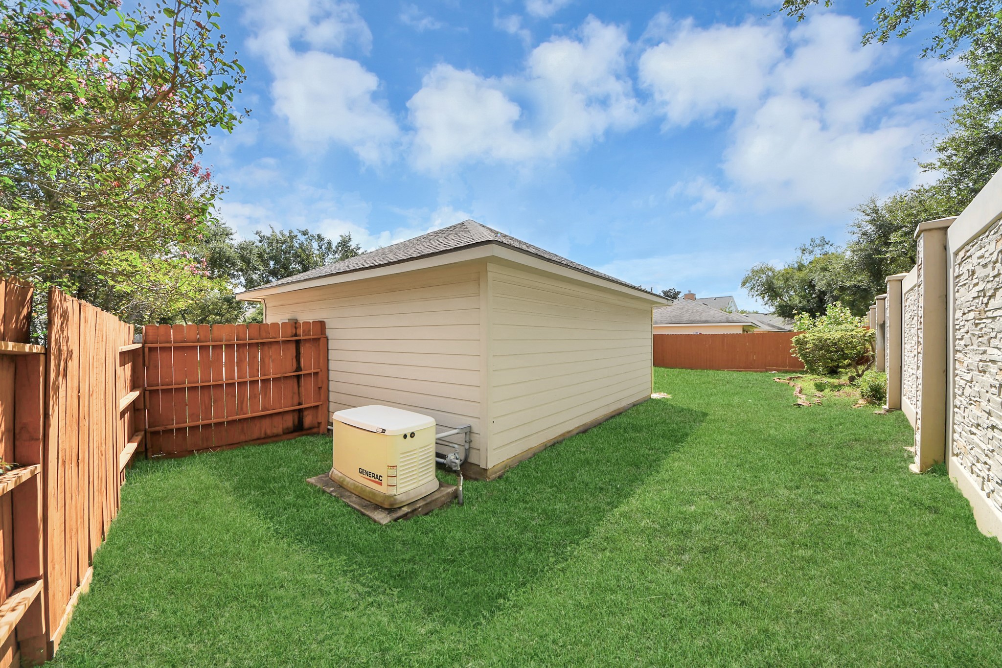 Spacious backyard featuring lush green grass, a sturdy wooden fence for privacy, and a convenient storage shed.