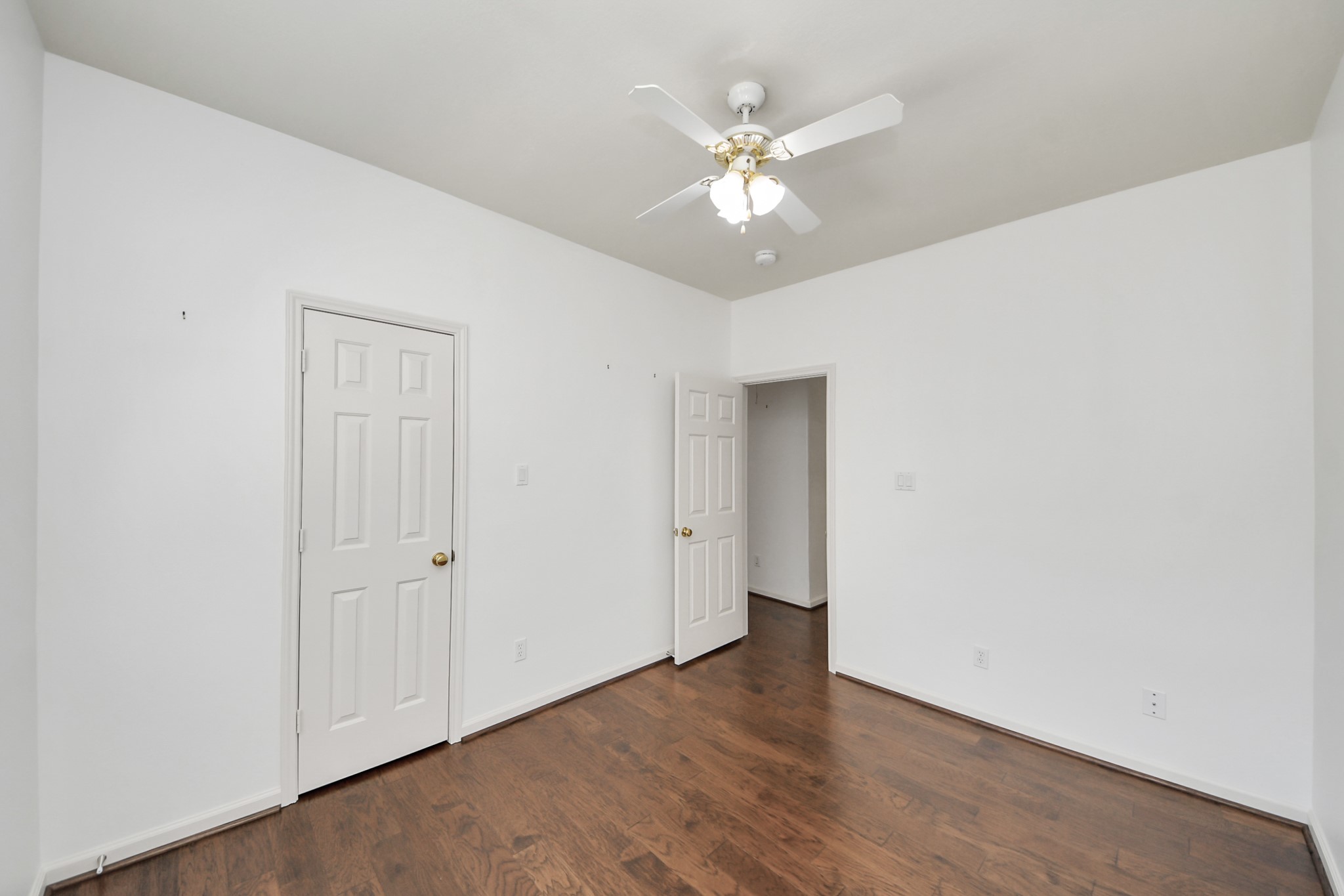 Bright and inviting room featuring hardwood floors, a ceiling fan, and ample natural light.