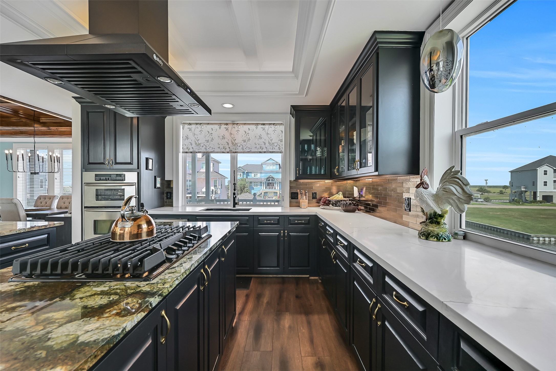 Hand-built coffered judges ceiling, glass-door upper cabinets, and Della Terra quartz perimeter counters. This is the kitchen other Harborwalk homes don't have.