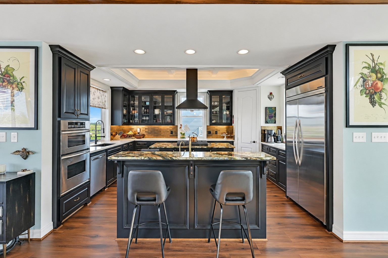 Commercial KitchenAid refrigerator. GE Monogram beverage fridge. KitchenAid wall oven and microwave. Custom freestanding hood over the center island. Every detail intentional.