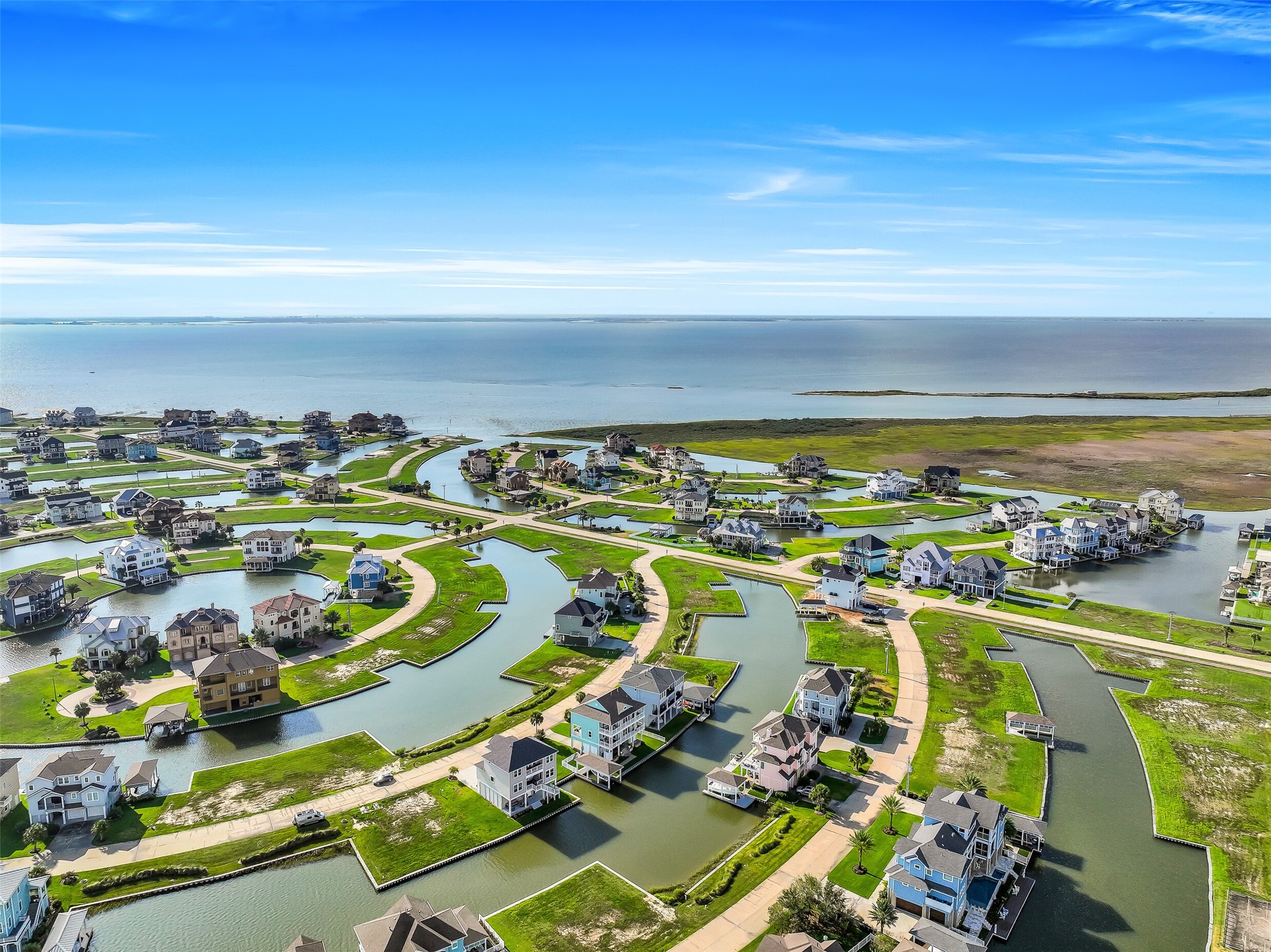 From above you can see exactly why Harborwalk is unlike anything else on the Gulf Coast. Manicured landscaped reserves, winding canals, a full-service marina, and a manned entry gate  all surrounding one of the most completely rebuilt waterfront homes in the community. This is 12 Fleming from the air, and the view only gets better from the inside.