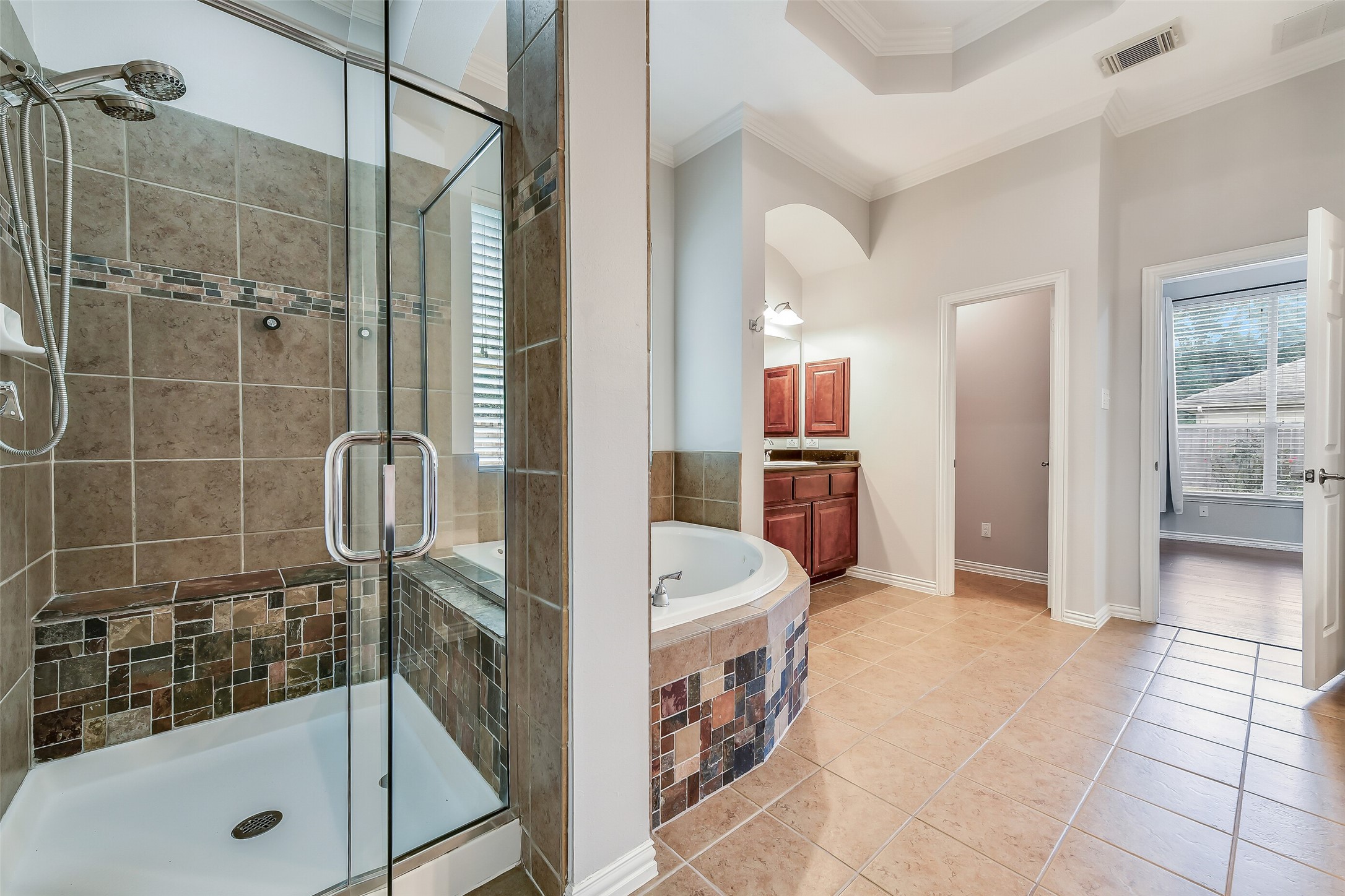This view highlights the second sink and vanity area along with the dual showerheads in the walk-in shower.