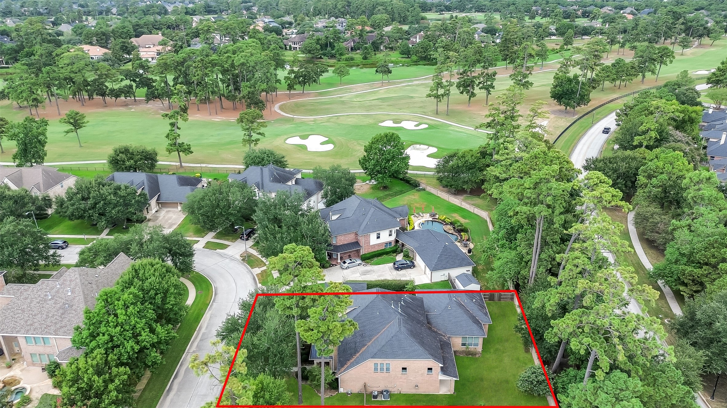 This aerial view highlights the home's proximity to the golf course. The wooded area directly behind the home runs along a walking trail, offering complete privacy with no rear neighbors.