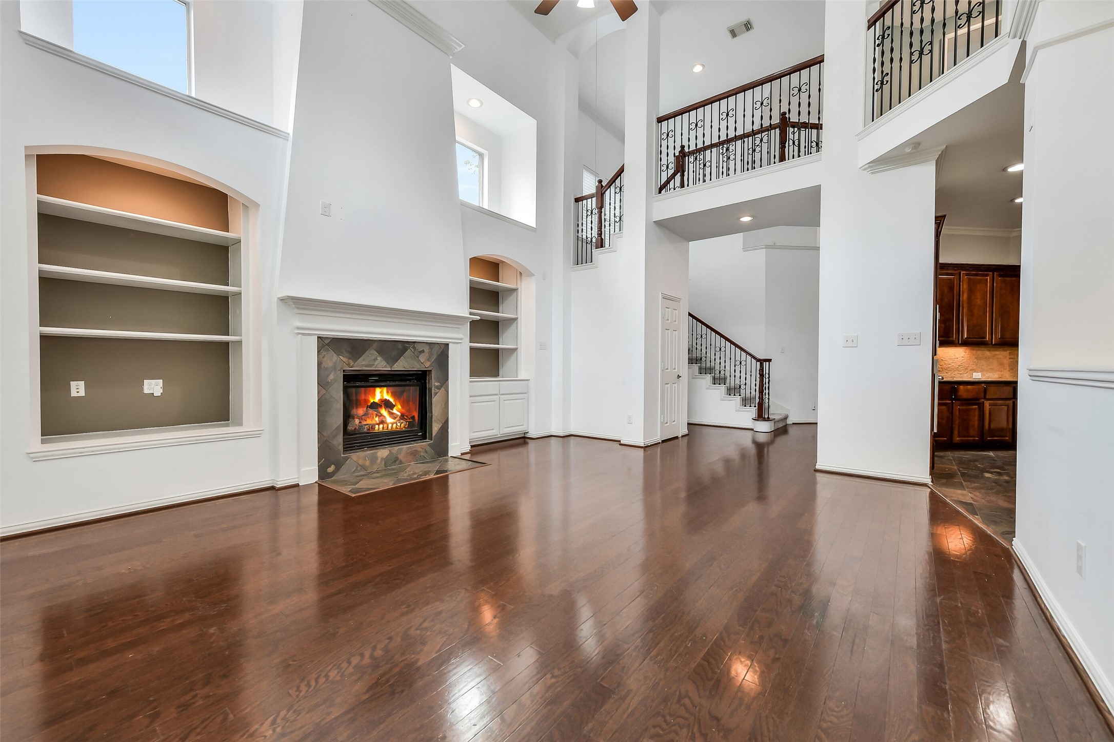 This view showcases one of the home's two stairways with classic wrought-iron railings, highlighting the effortless open layout between the living room and kitchen. Wired for surround sound.