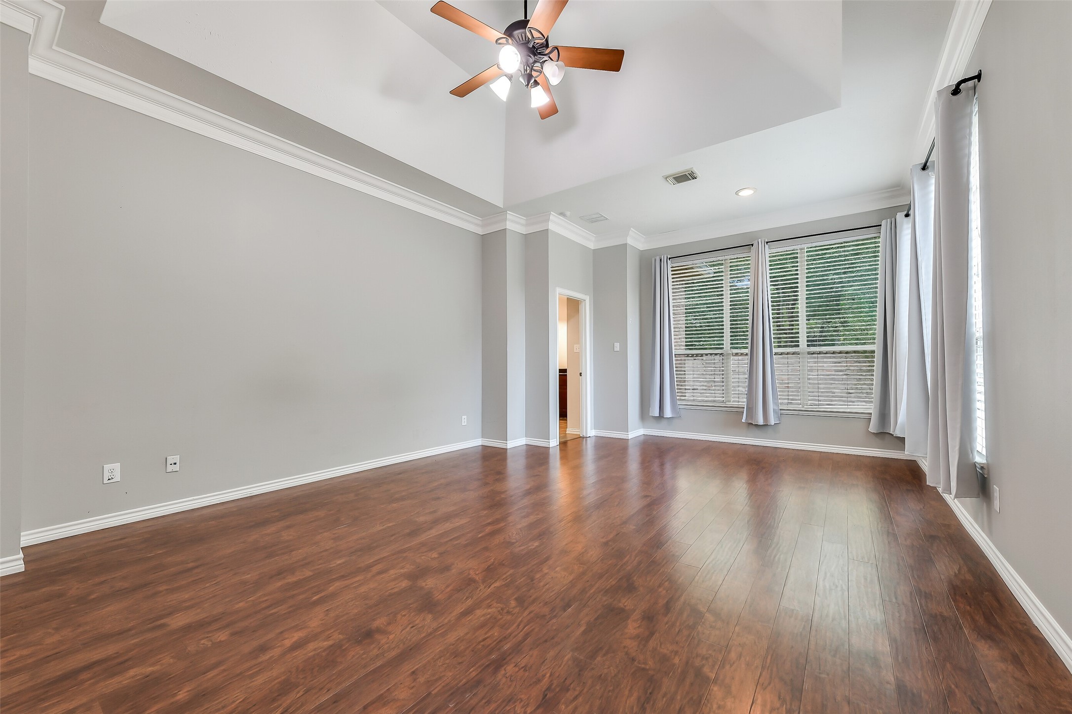 The spacious primary bedroom includes a cozy sitting area, vaulted ceiling, double crown molding, floor-to-ceiling windows, custom drapery and en-suite bathroom.