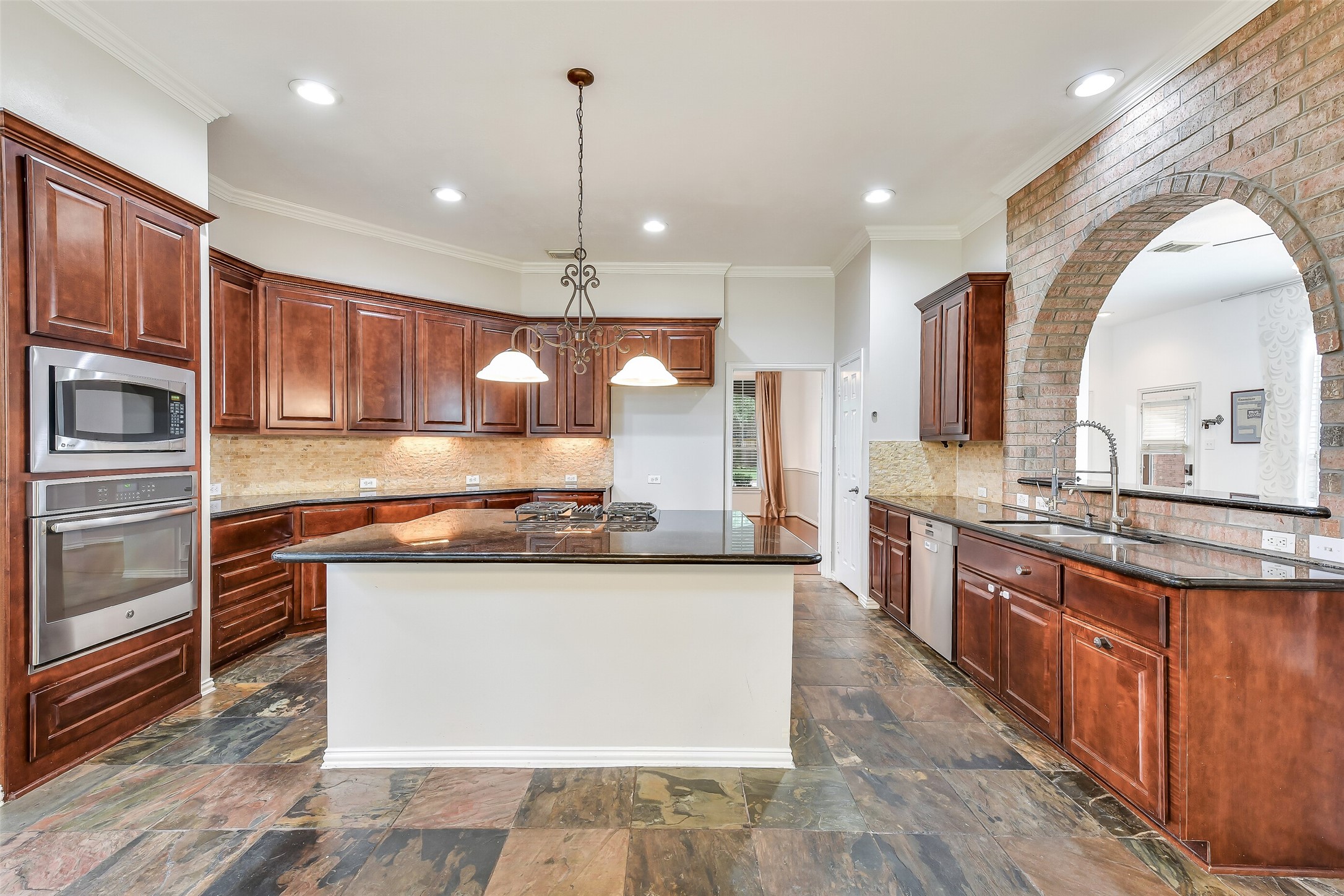 An entertainer and chef's dream, this kitchen boasts a massive island with seating for four, GE gas cooktop, generous cabinetry, under-cabinet lighting, built-in microwave and range, all set against a stylish brick accent wall.