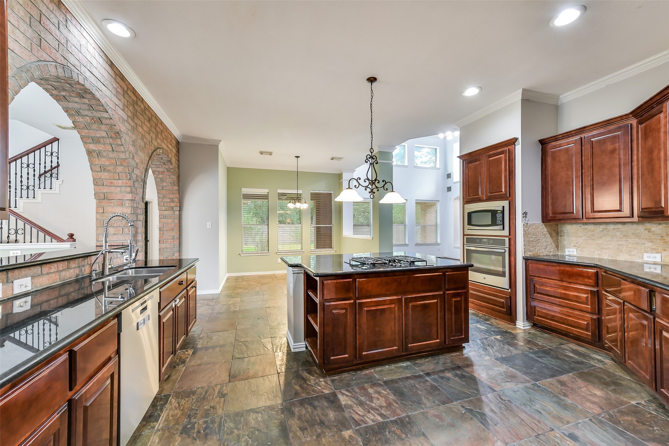 This view highlights the kitchen's stainless steel appliances, extra island storage, and an adjacent breakfast nook with views of the backyard.