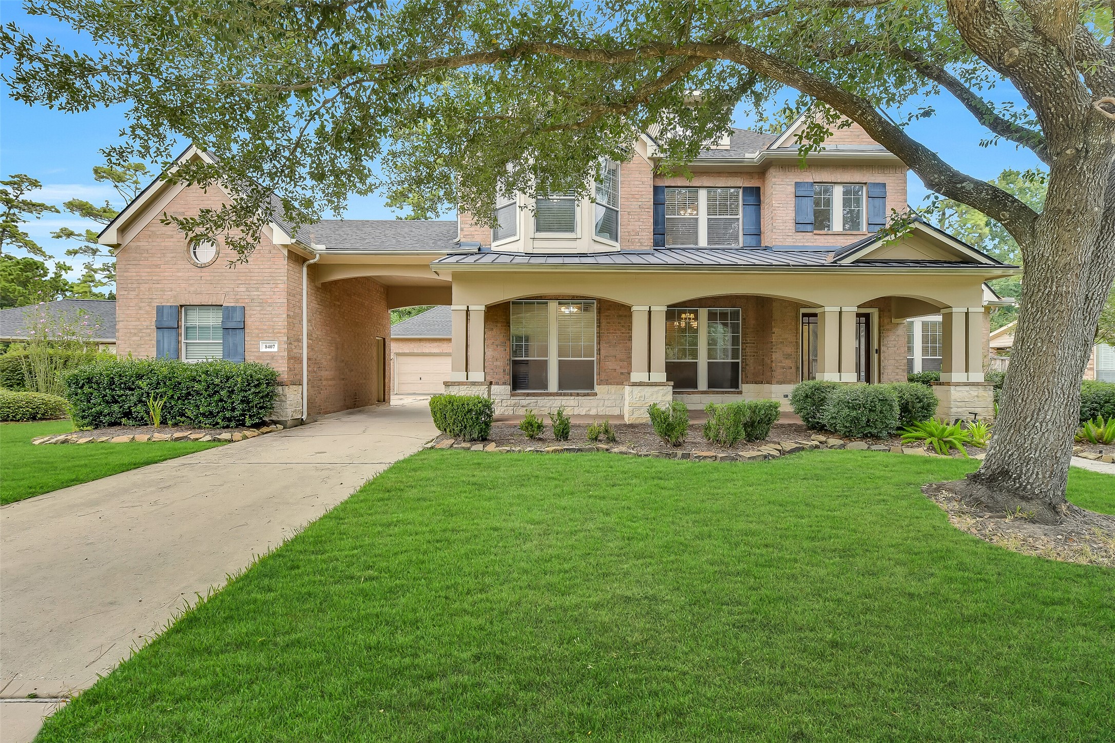 This stunning home in the golf course community of Fall Creek features a charming two-story elevation with a combination of classic brick and stone accents, a porte-cochre leading to the driveway, and a welcoming covered front porch surrounded by mature shade trees and manicured landscaping