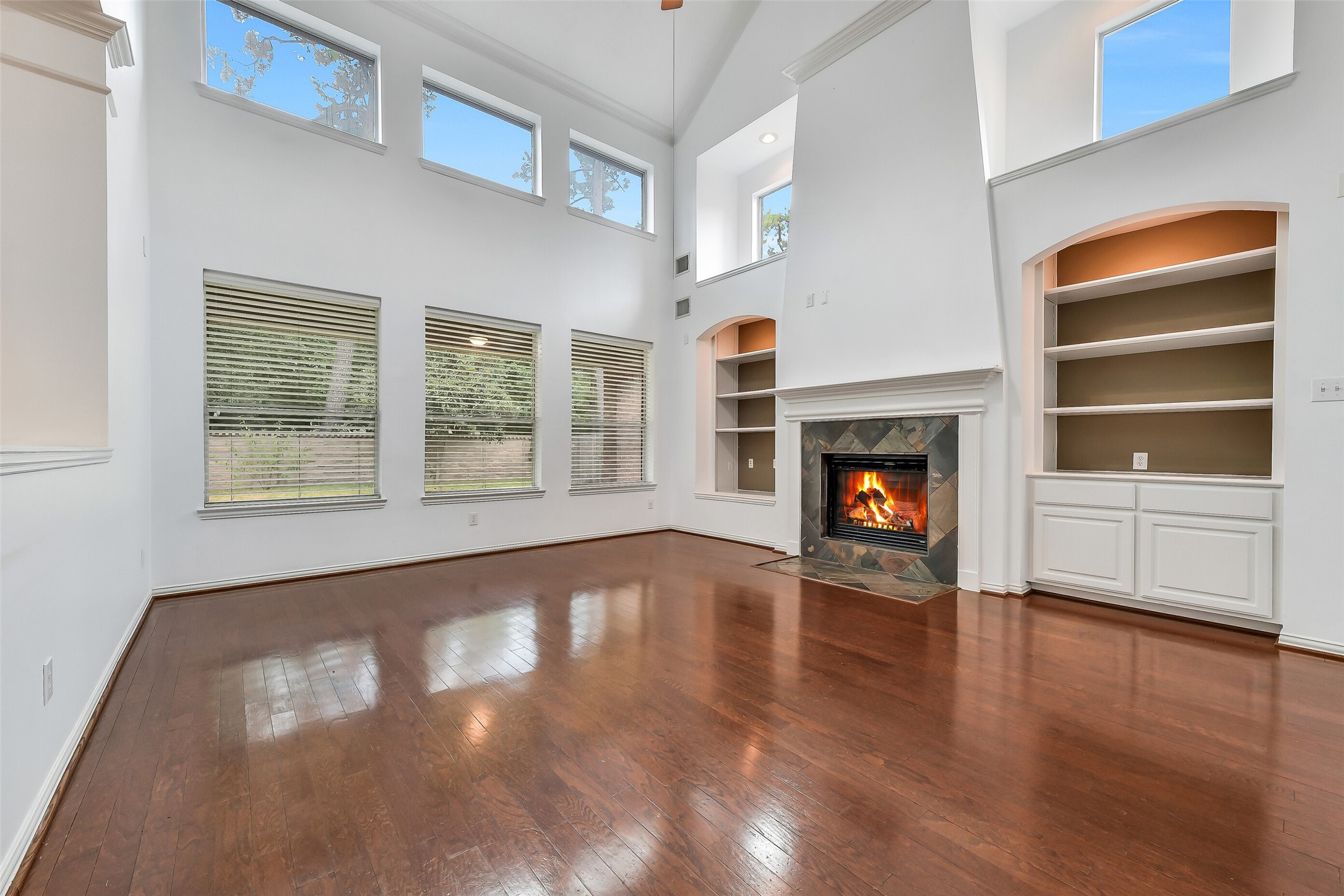 The family room boasts soaring ceilings, custom built-in cabinetry, and a gas log fireplace, while ample accent windows fill the space with bright, natural light.